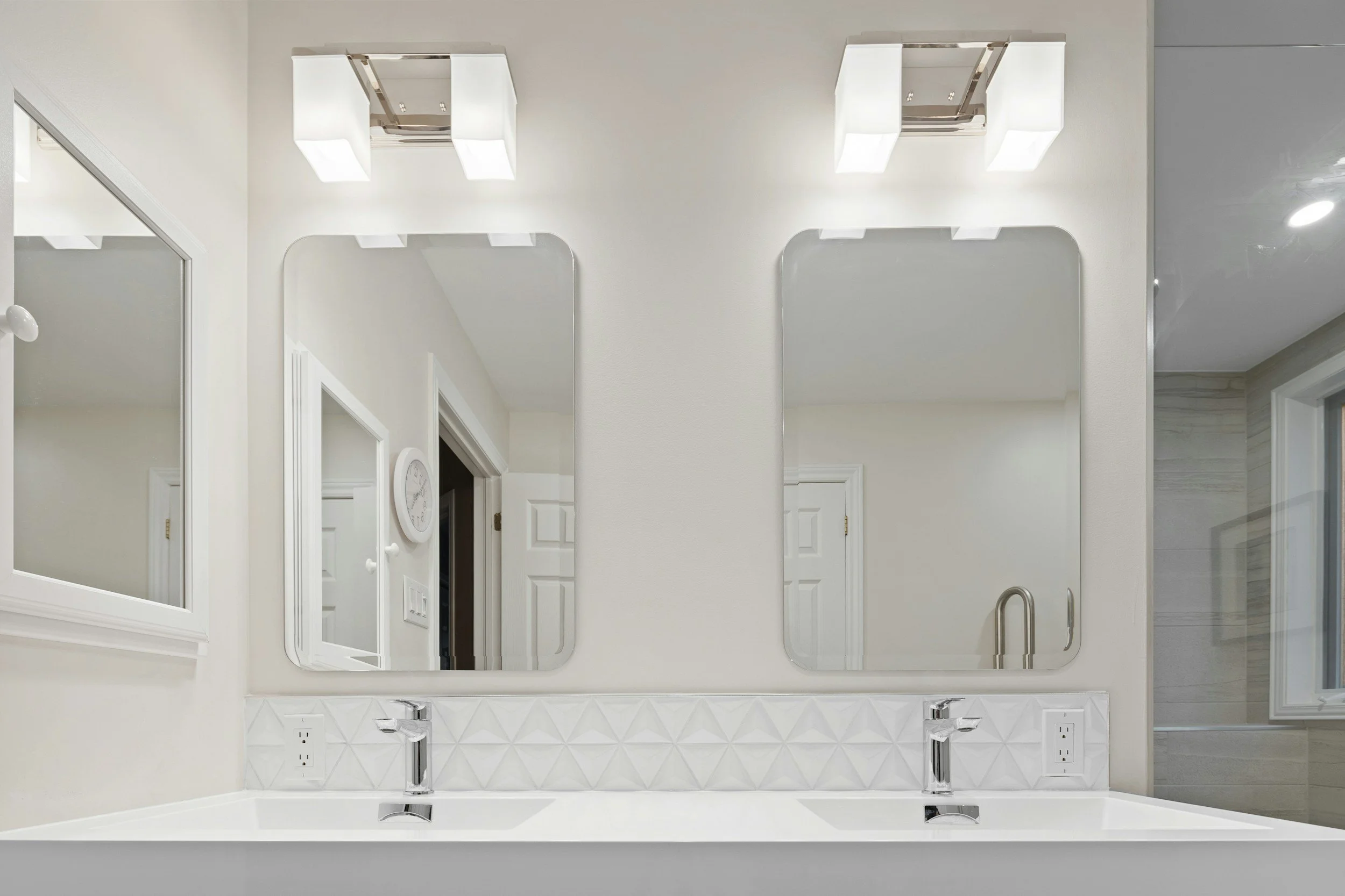 Double vanity with mirrors and layered lighting in a remodeled primary bathroom