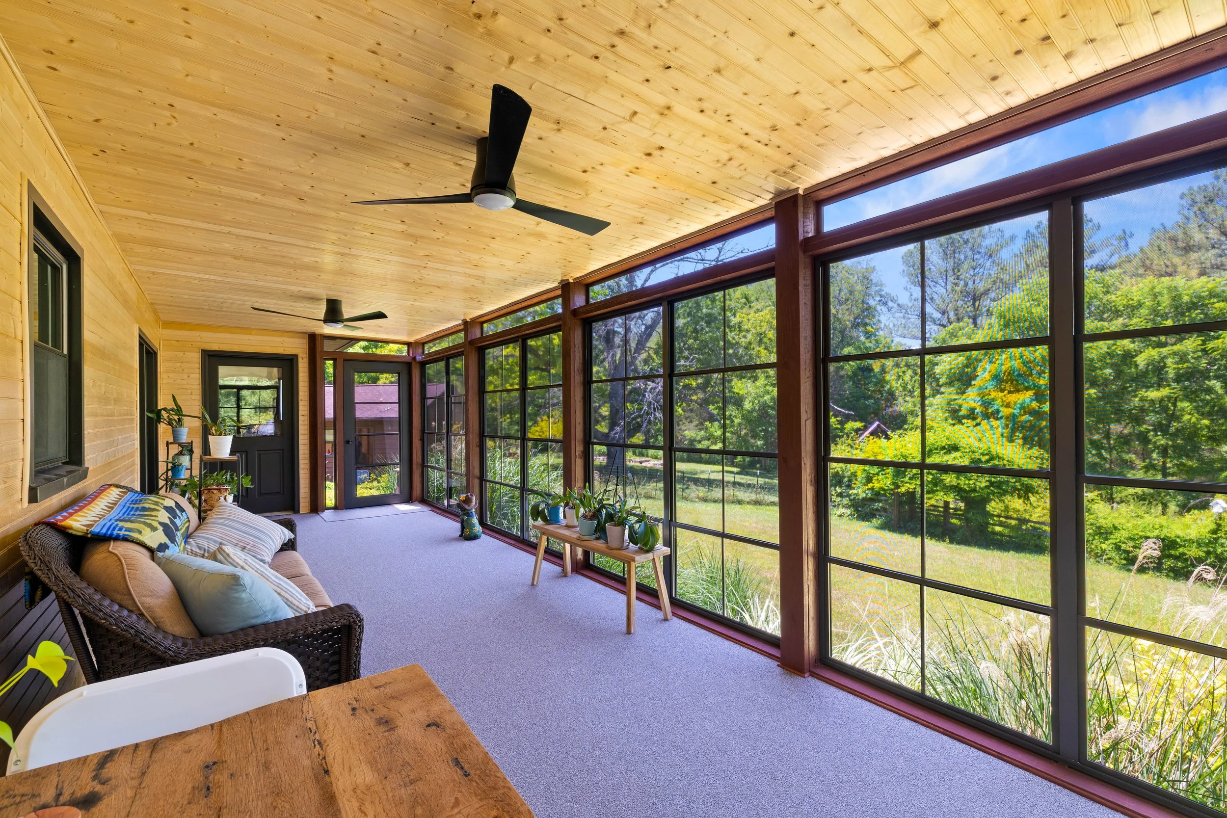 Interior of a Blacksburg three-season room with SunSpace window panels closed and views of the backyard.
