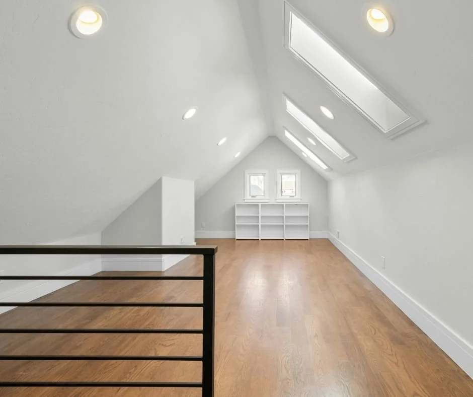 Open finished attic with sloped ceilings, windows, and hardwood flooring