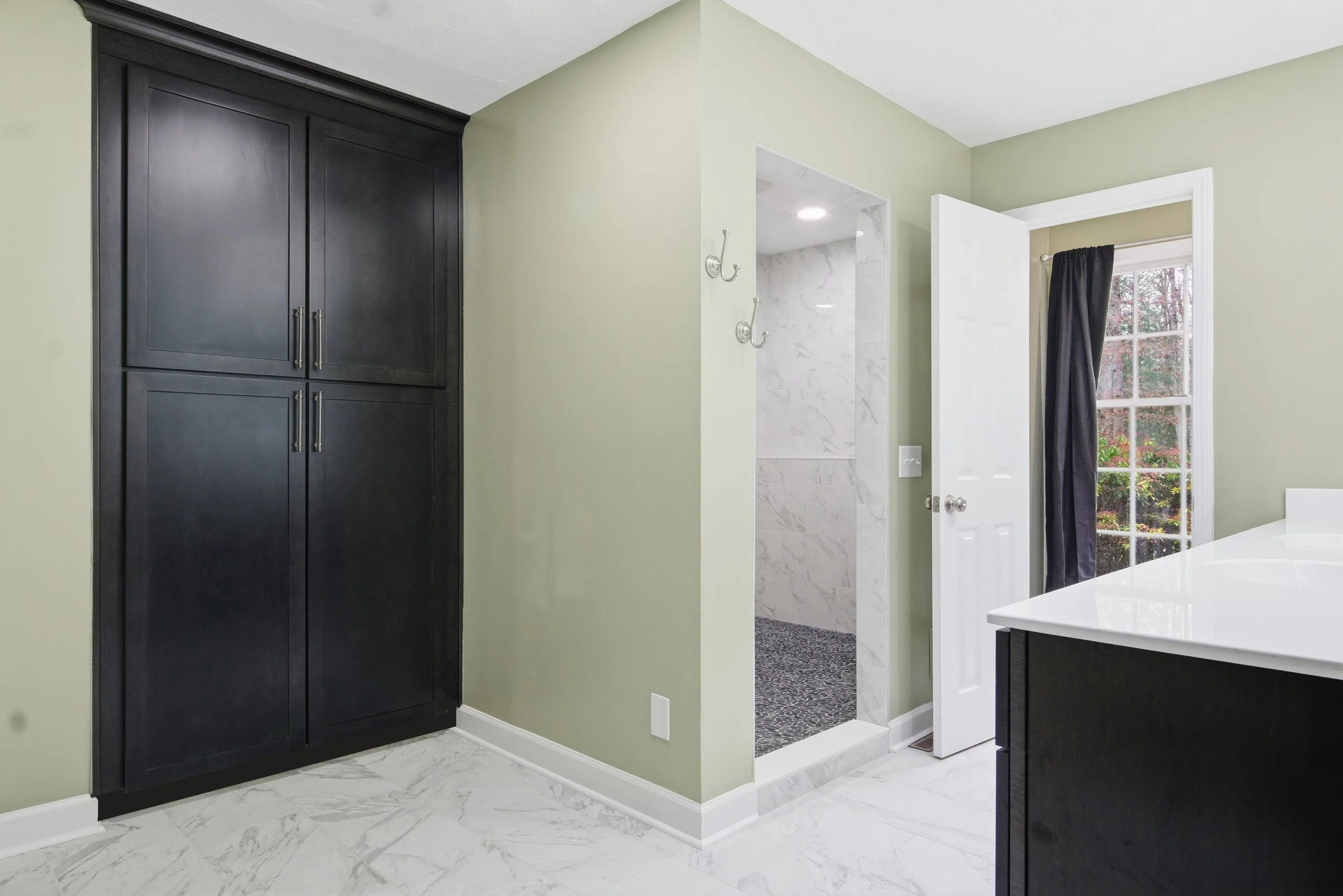 Remodeled primary bathroom with a large walk-in shower, dark wood vanity and cabinets, and light sage green walls