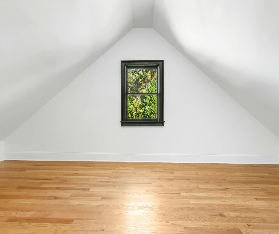 Finished attic with sloped ceiling and window bringing natural light into the space