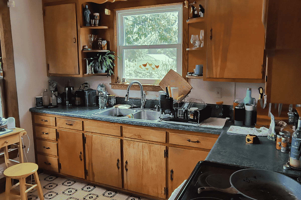 Kitchen before renovation in a 1919 Sears kit house in Pembroke, Virginia, with older wood cabinets and limited counter space.