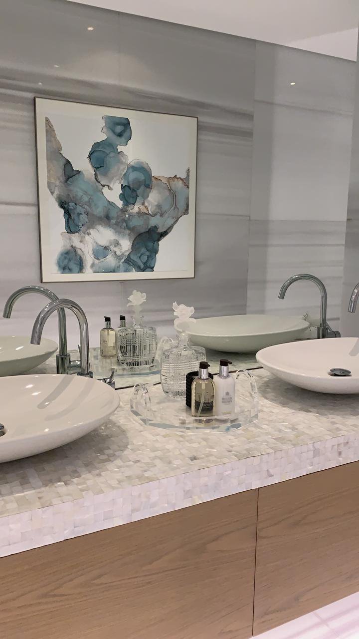 Modern bathroom with two sinks, decorative bottles, and abstract artwork on the wall.
