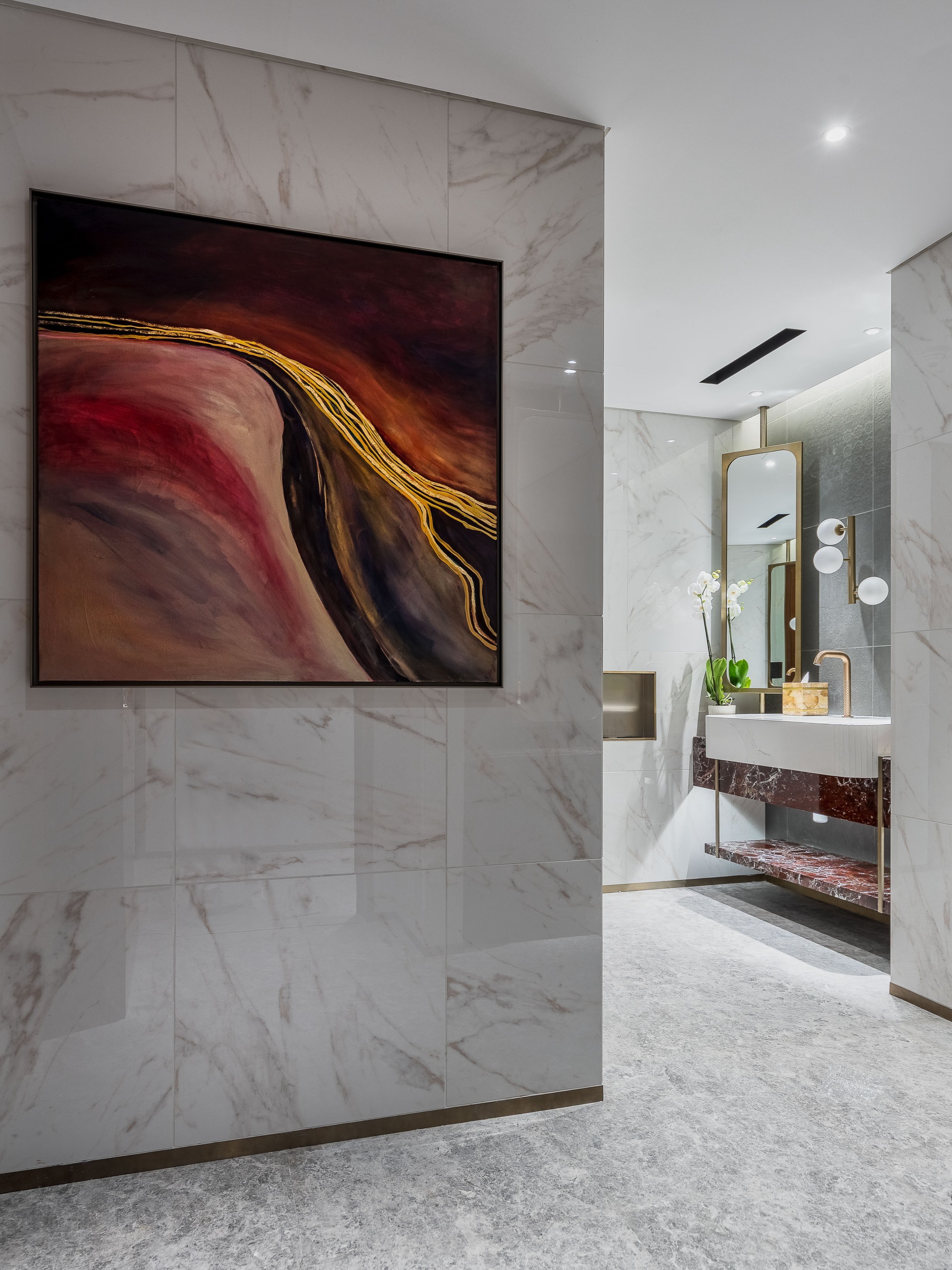 Modern bathroom in the Burj Al Arab hotel with marble walls, abstract art, and a vanity with mirror.