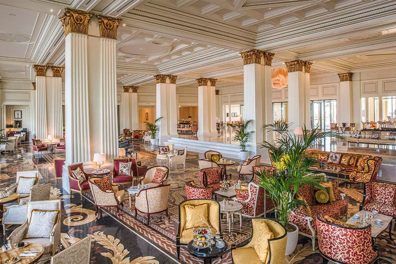 Luxurious hotel lobby with plush seating, ornate columns, and lavish decor.