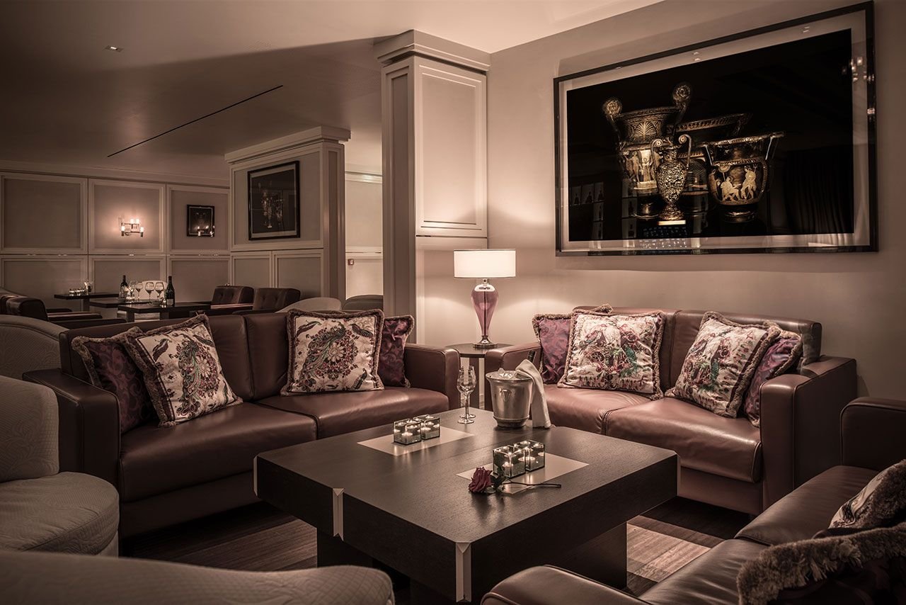 Luxury hotel lounge with leather sofas, decorative pillows, modern art on walls, and ambient lighting.