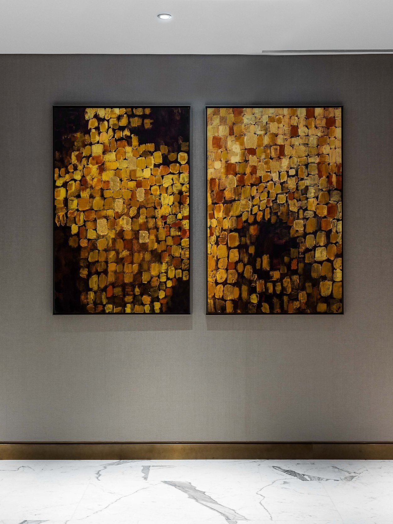 Two abstract paintings with gold leaf square patterns on a gray wall in a modern interior in the Burj Al Arab Hotel, Dubai.