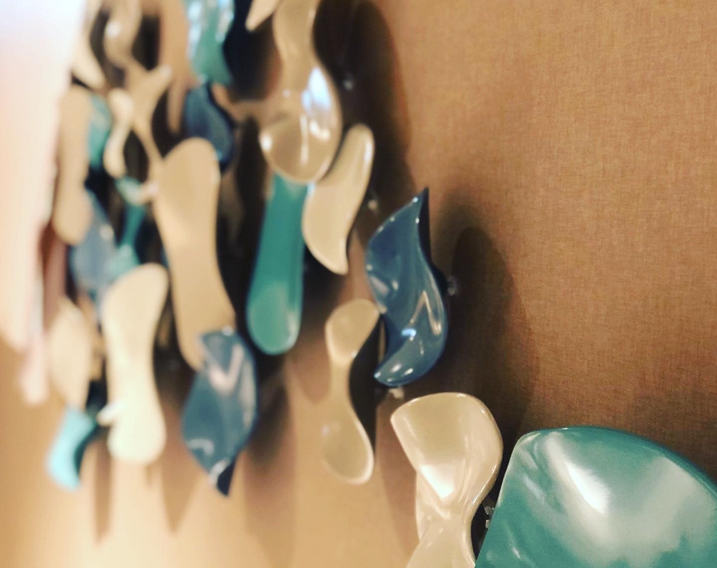Abstract wall art installation with blue and beige curved shapes on a brown background.