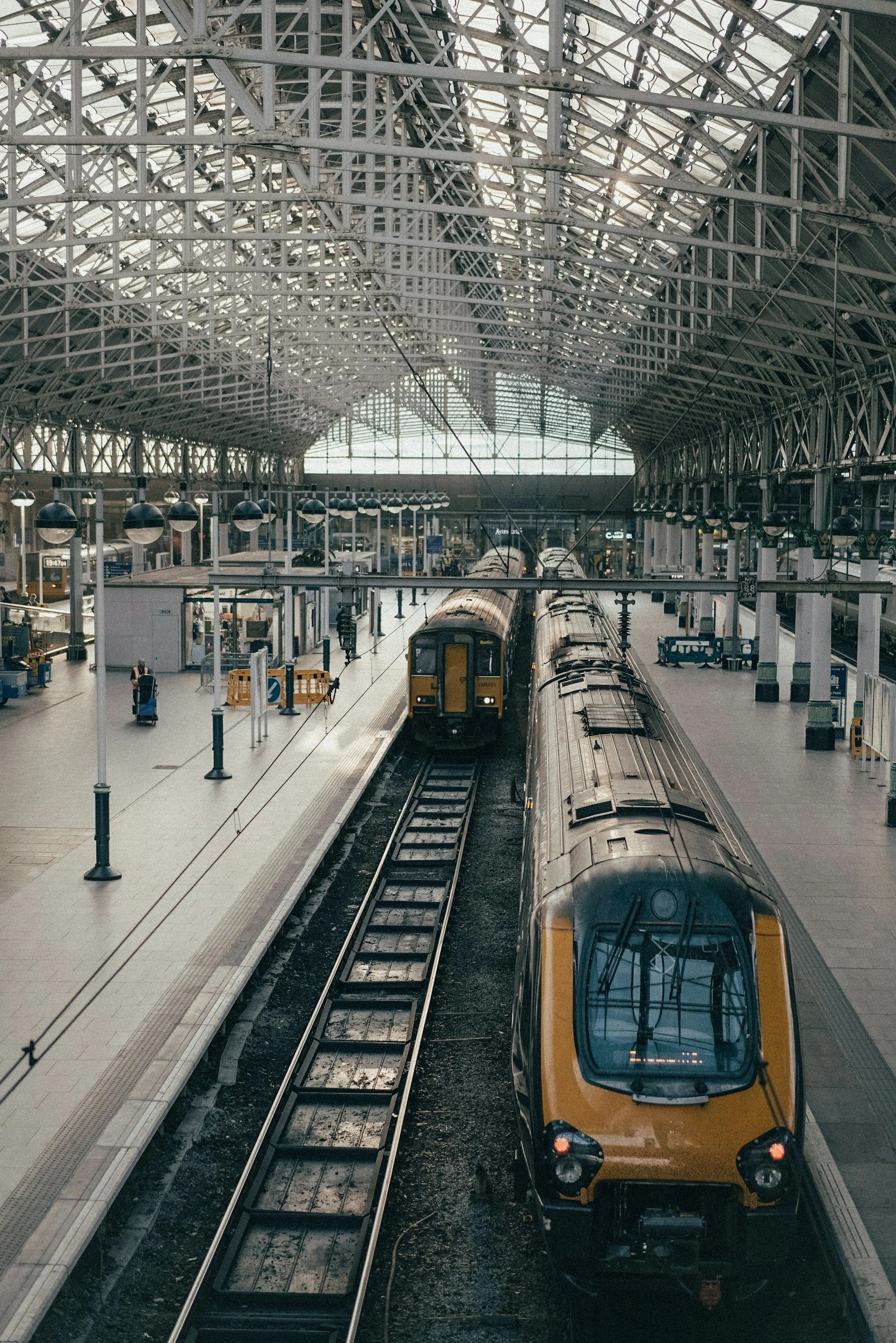 Interior of a train station with trains on tracks inside a large glass and steel structure.