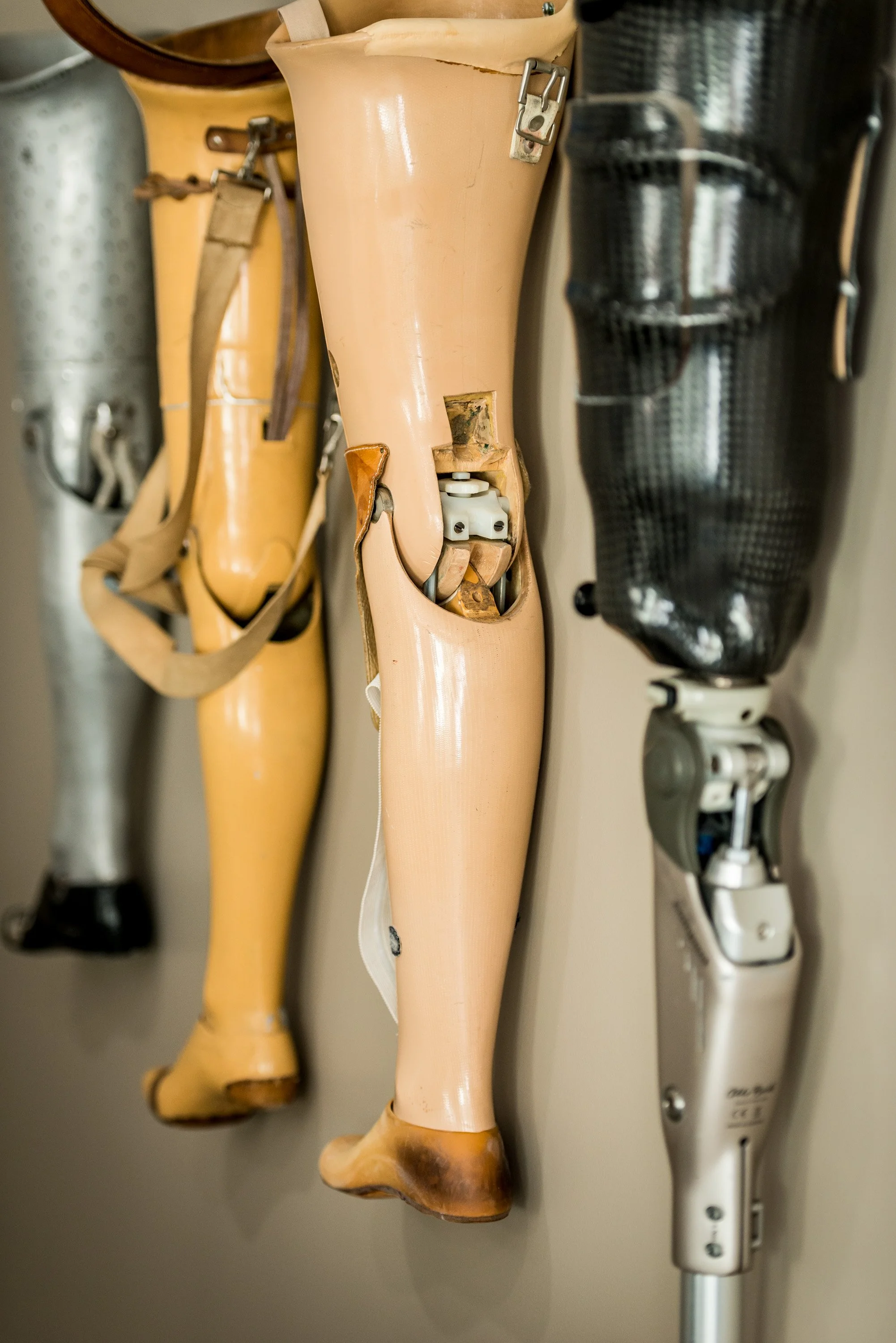 Collection of different prosthetic legs hanging on a wall.