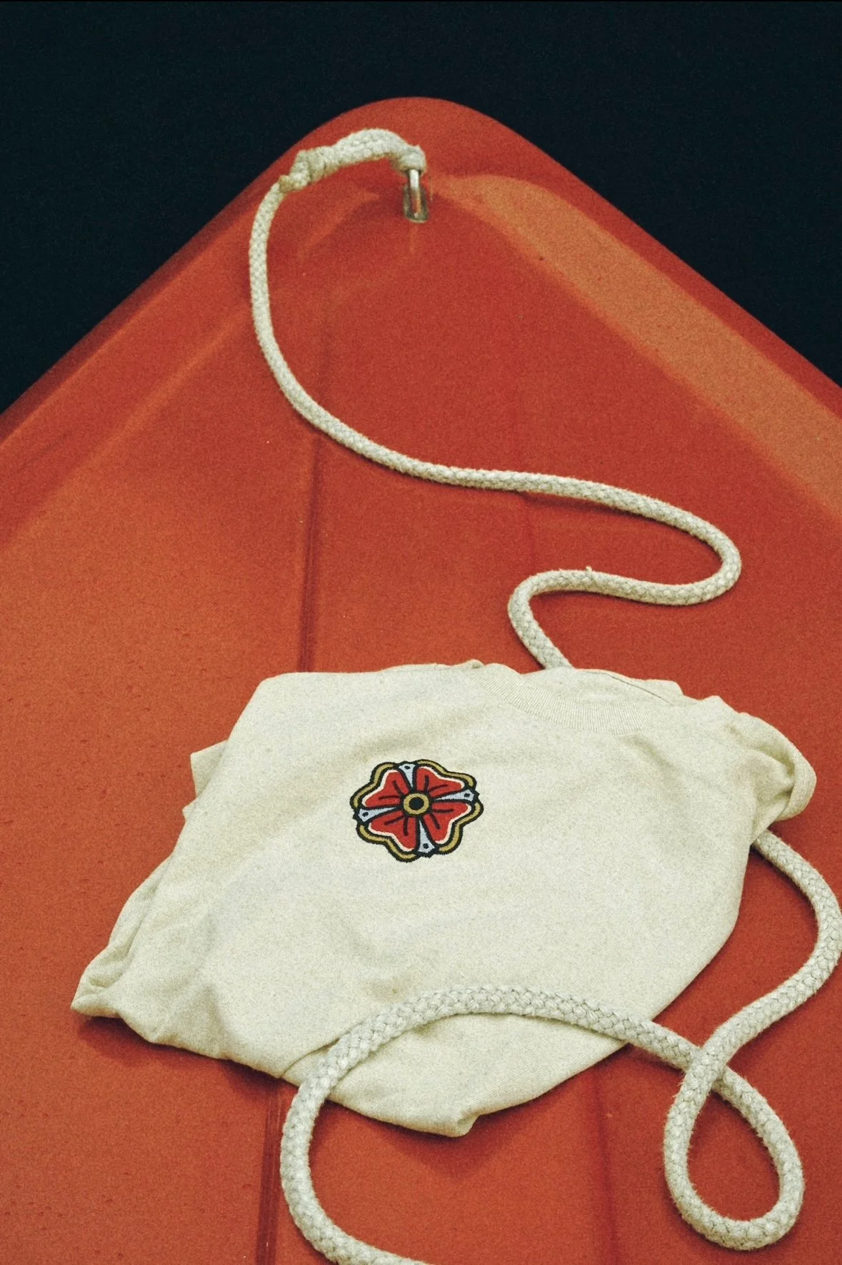 Ein rotes Notfallstation-Board mit einem weißen Seil und einem weißen Tuch mit einer roten Blume auf der Vorderseite.