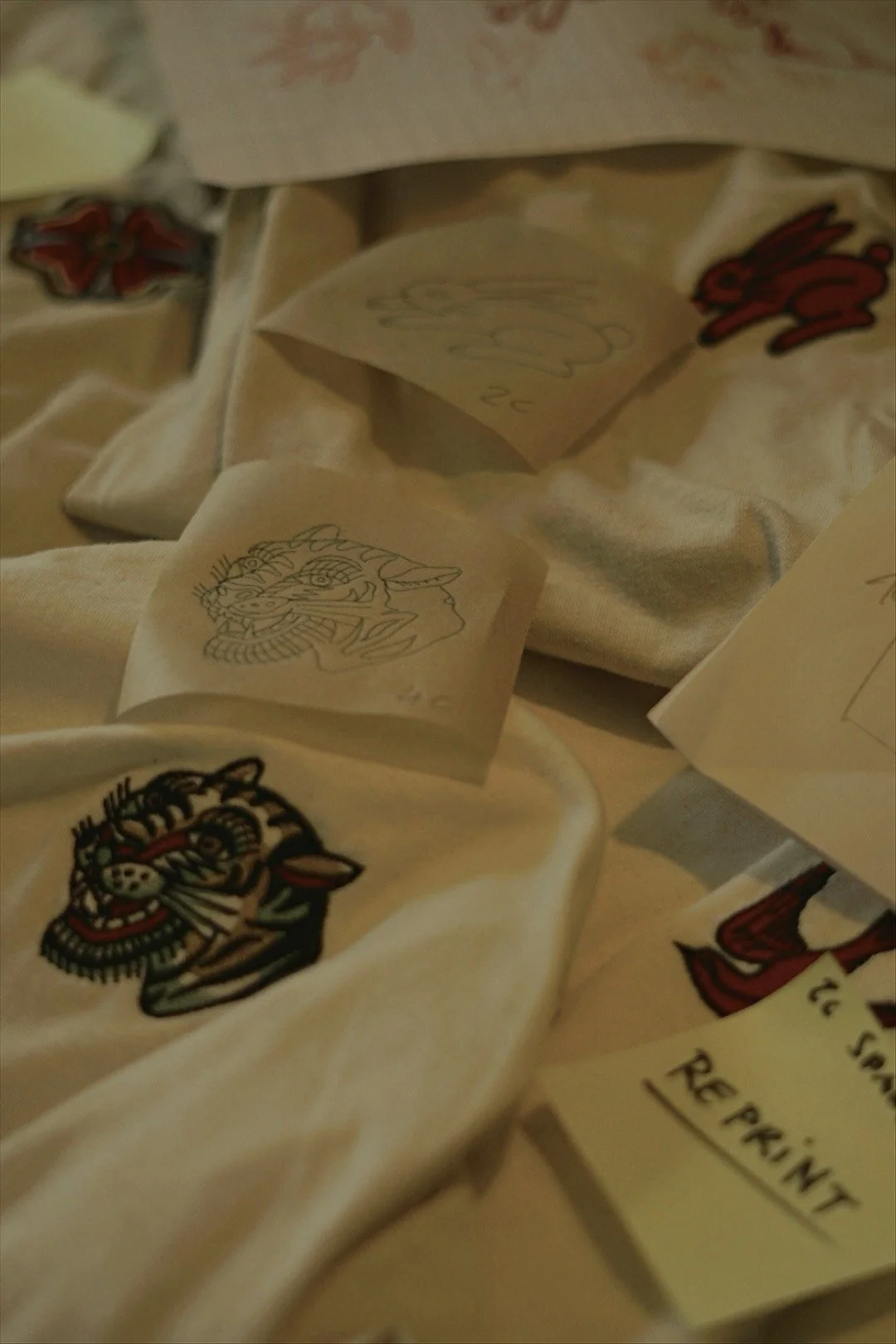 Verschiedene Papierschnitte mit asiatischen Tiermotiven und Texten, teilweise in schwarzen und roten Farben, liegen verstreut auf einem beige Stoff.