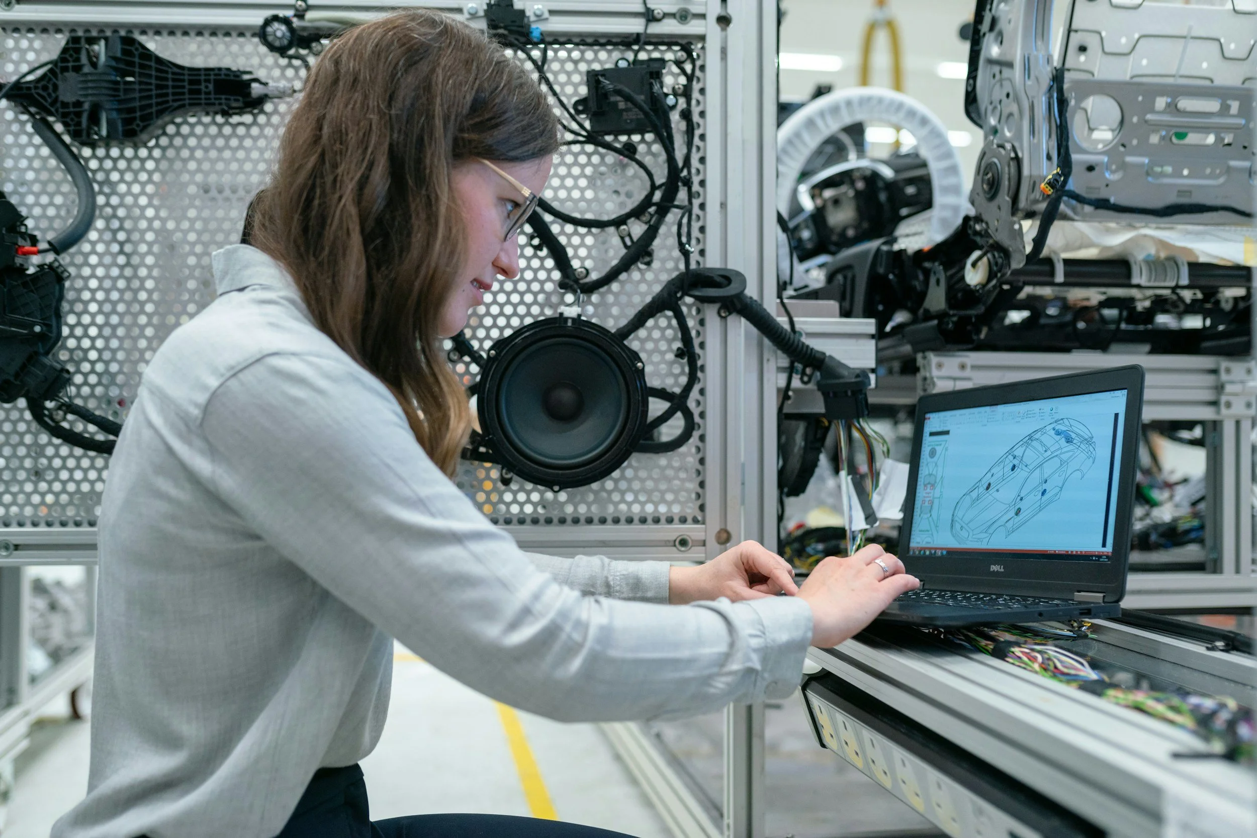 A young woman works on the engineering a car