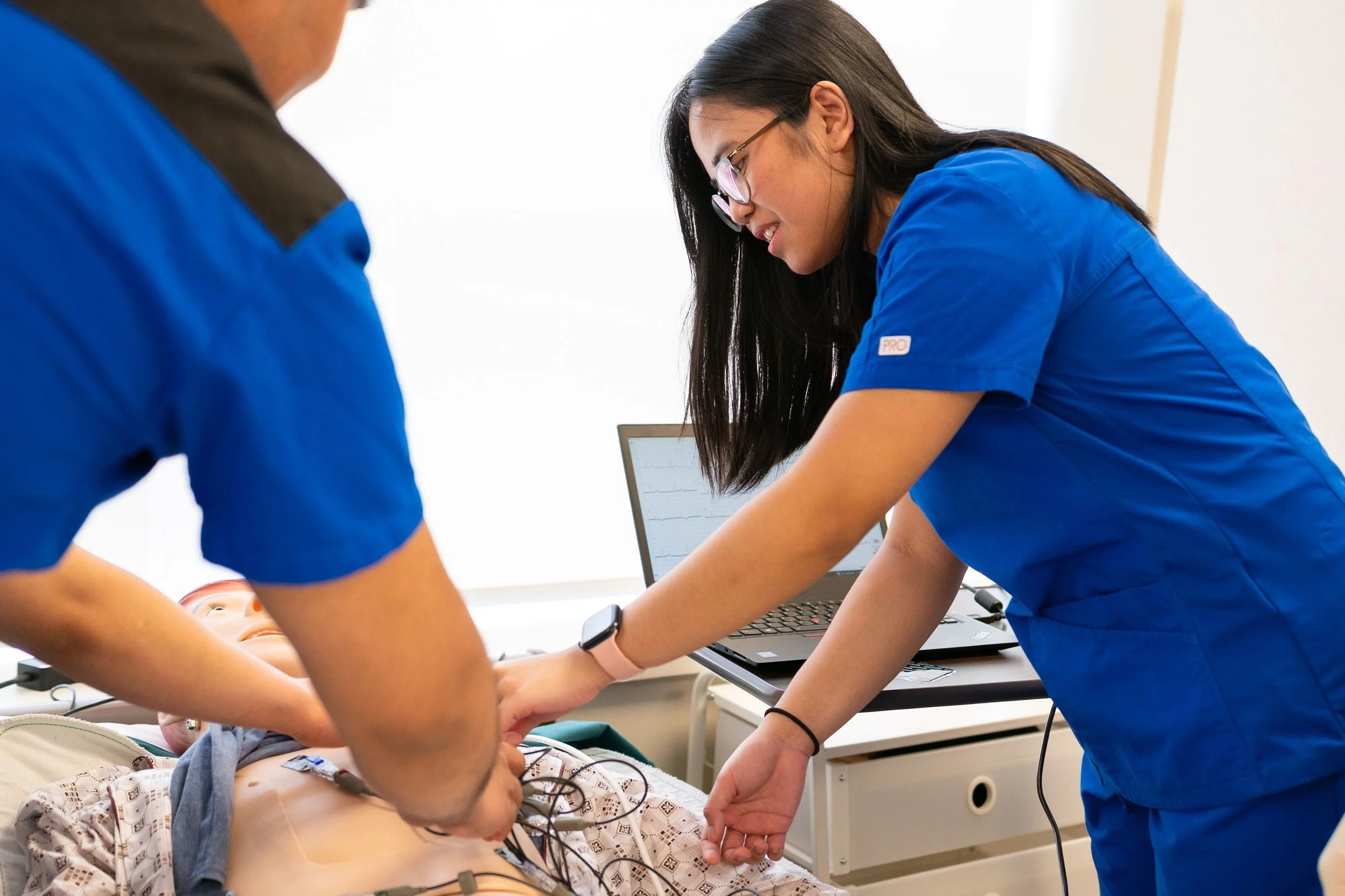 Two nursing students practice on a mannequin
