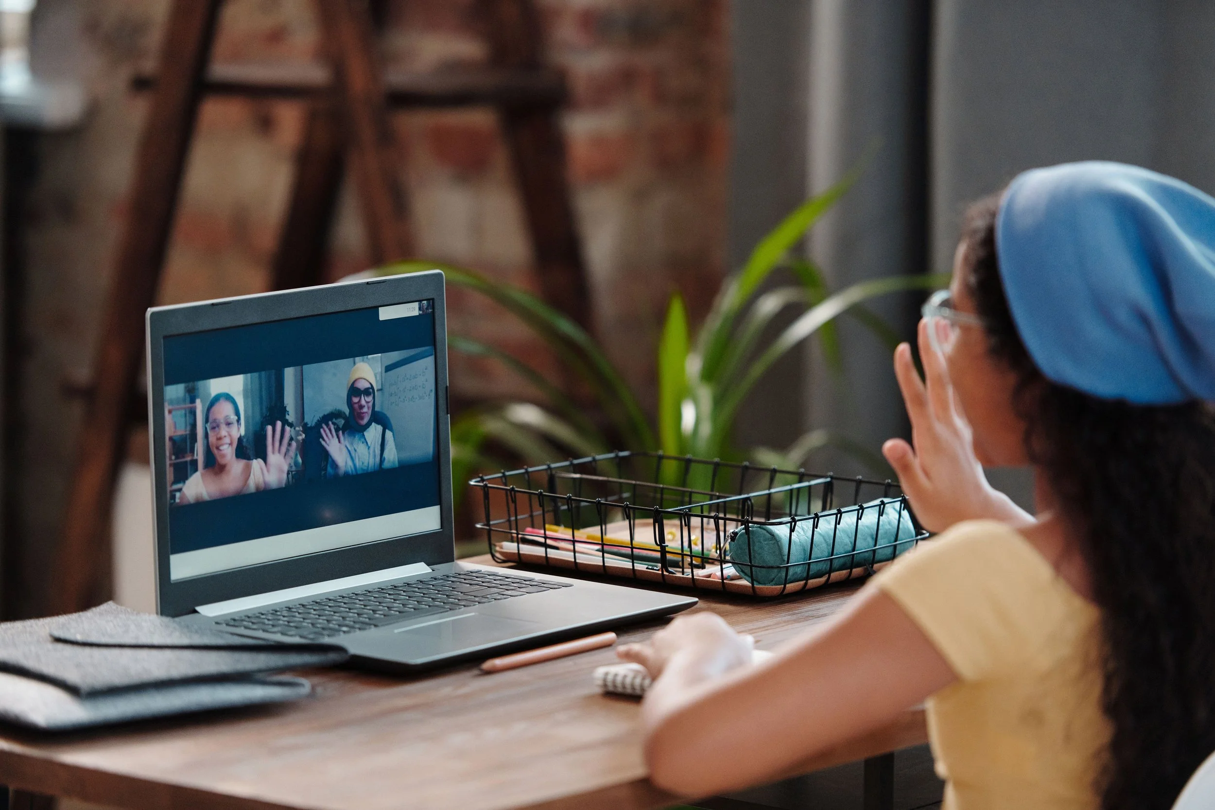 A student waves at her virtual teacher