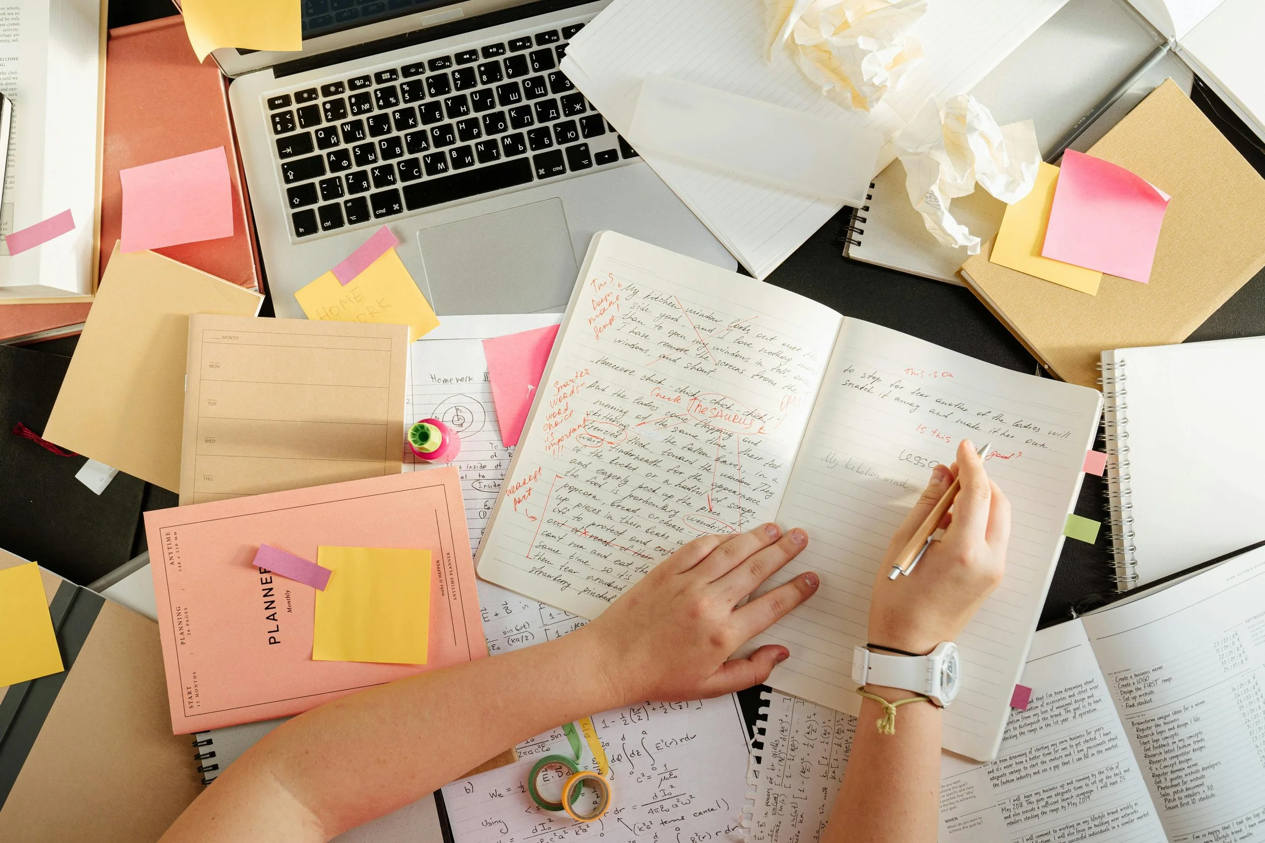 A desk covered in papers with someone working at it