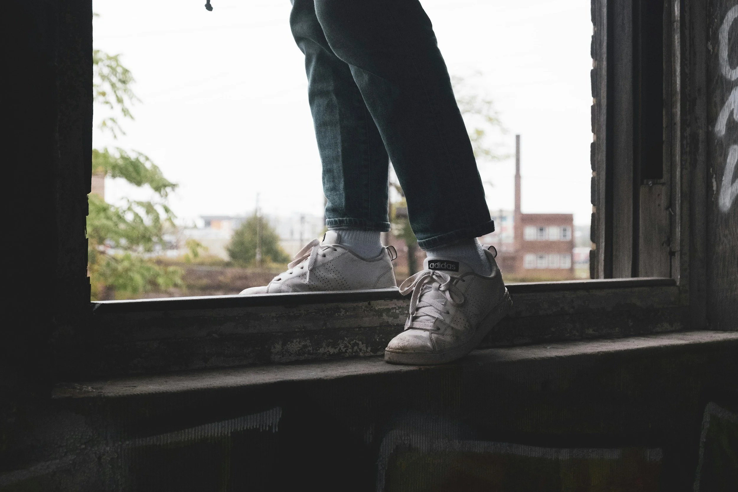 Shoes of a teen standing off a city windowsill, representing school stress and anxiety