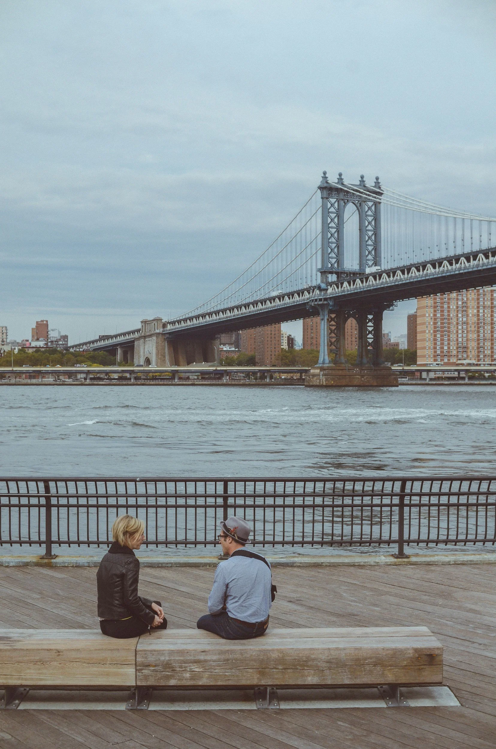 Couple sitting together by a bridge in New York City navigating divorce, separation, and co-parenting decisions