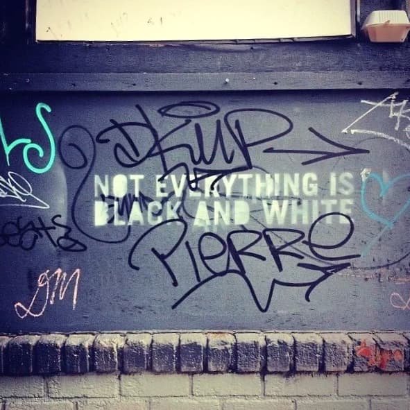 Wall art reading 'Not Everything Is Black and White' in a gender-affirming therapy office
