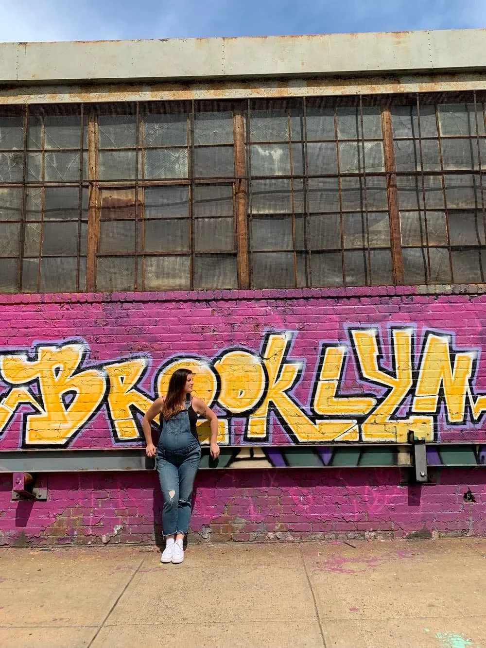 Pregnant woman standing in front of a colorful Brooklyn mural