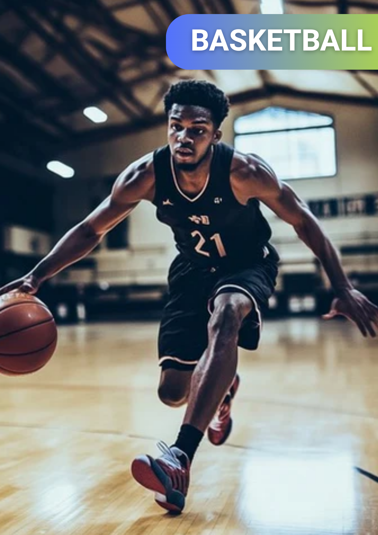 A young male basketball player in black uniform with the number 21 dribbling a basketball on a court inside a gymnasium.