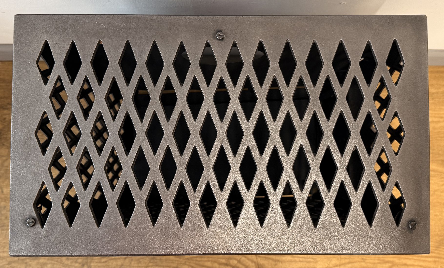 Top view of a French stove with diamond-shaped openings, mounted on a surface with visible screws.