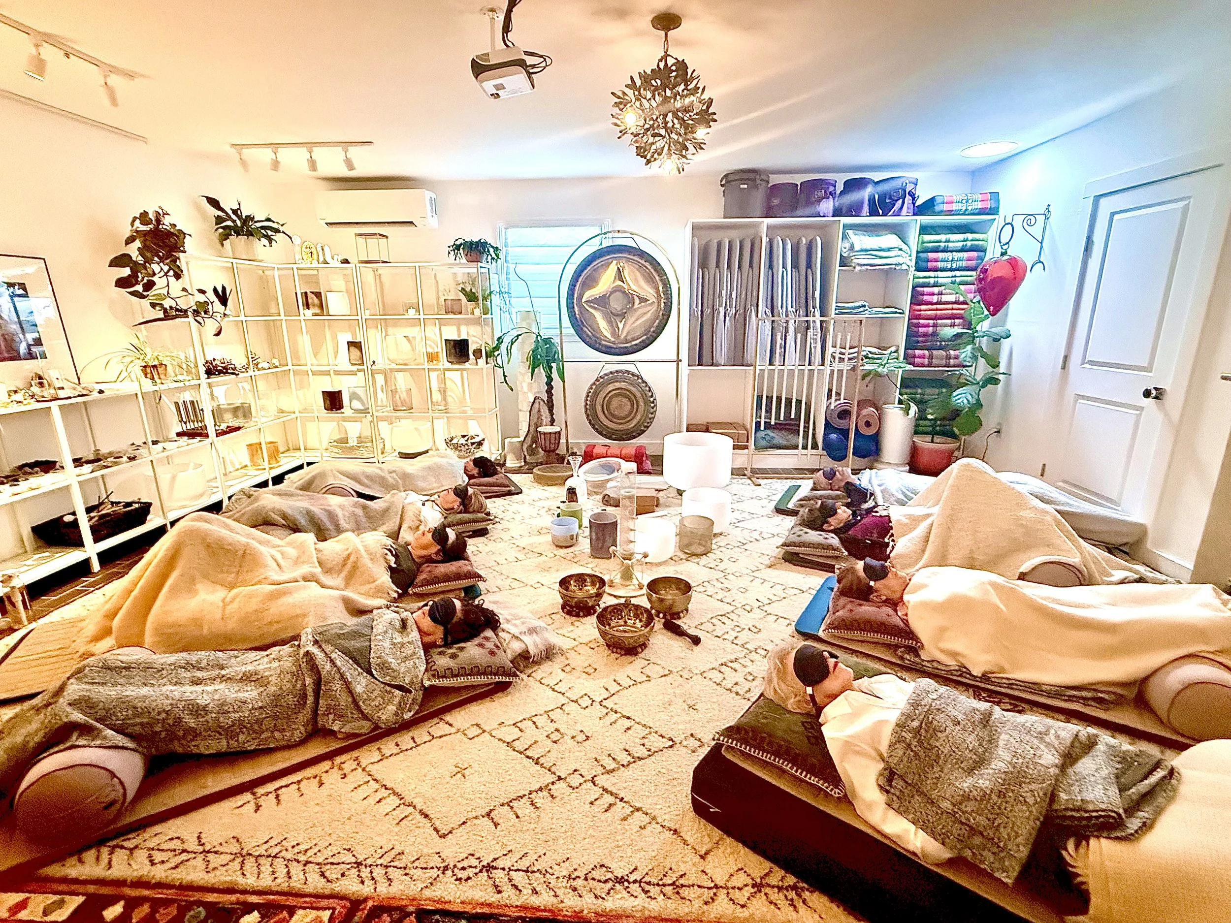 sound bath set up for 8 people, laying on yoga mats with eye masks and blankets