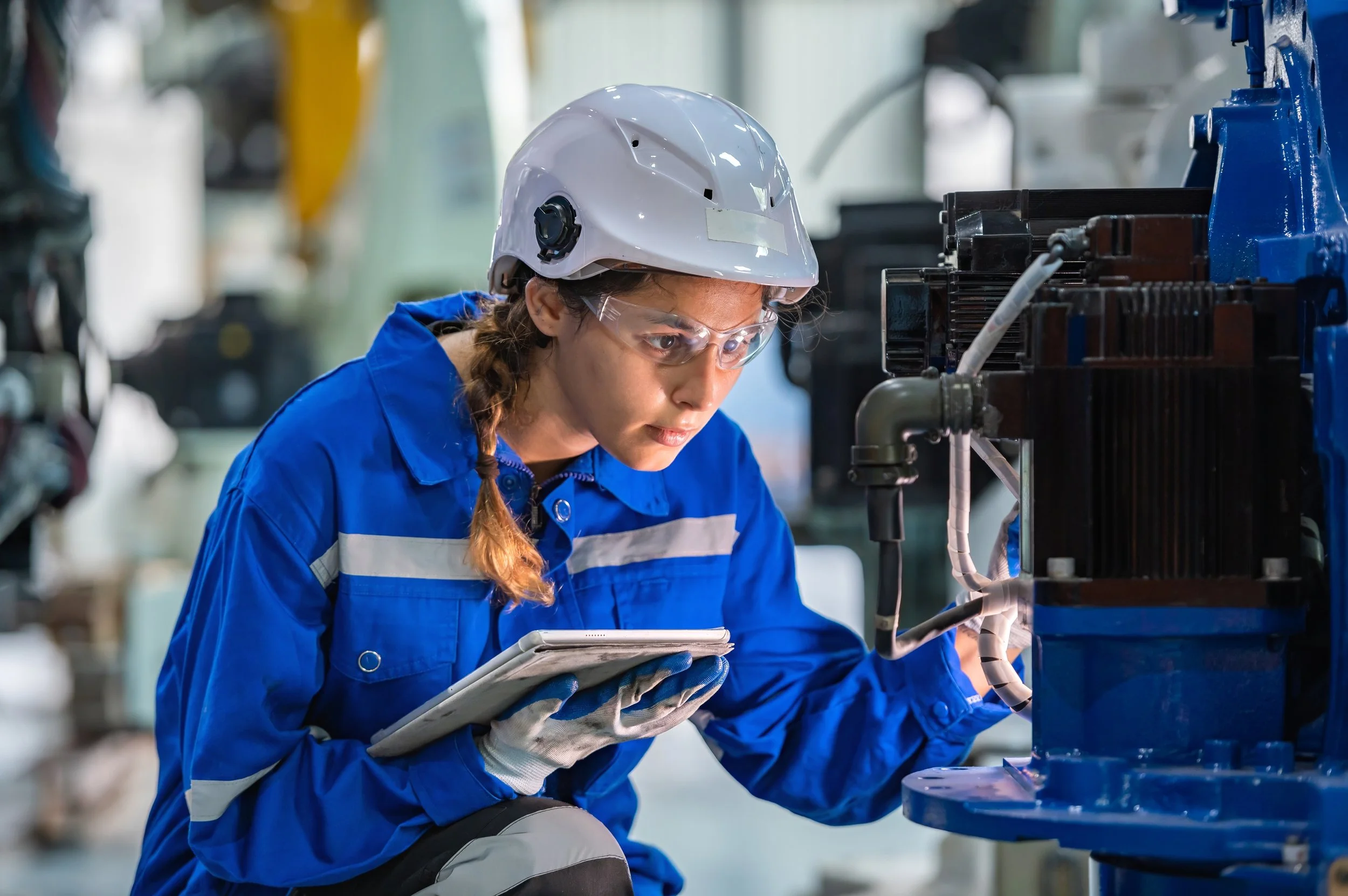 Woman in safety gear inspects factory machinery, leveraging private cellular for secure manufacturing connectivity