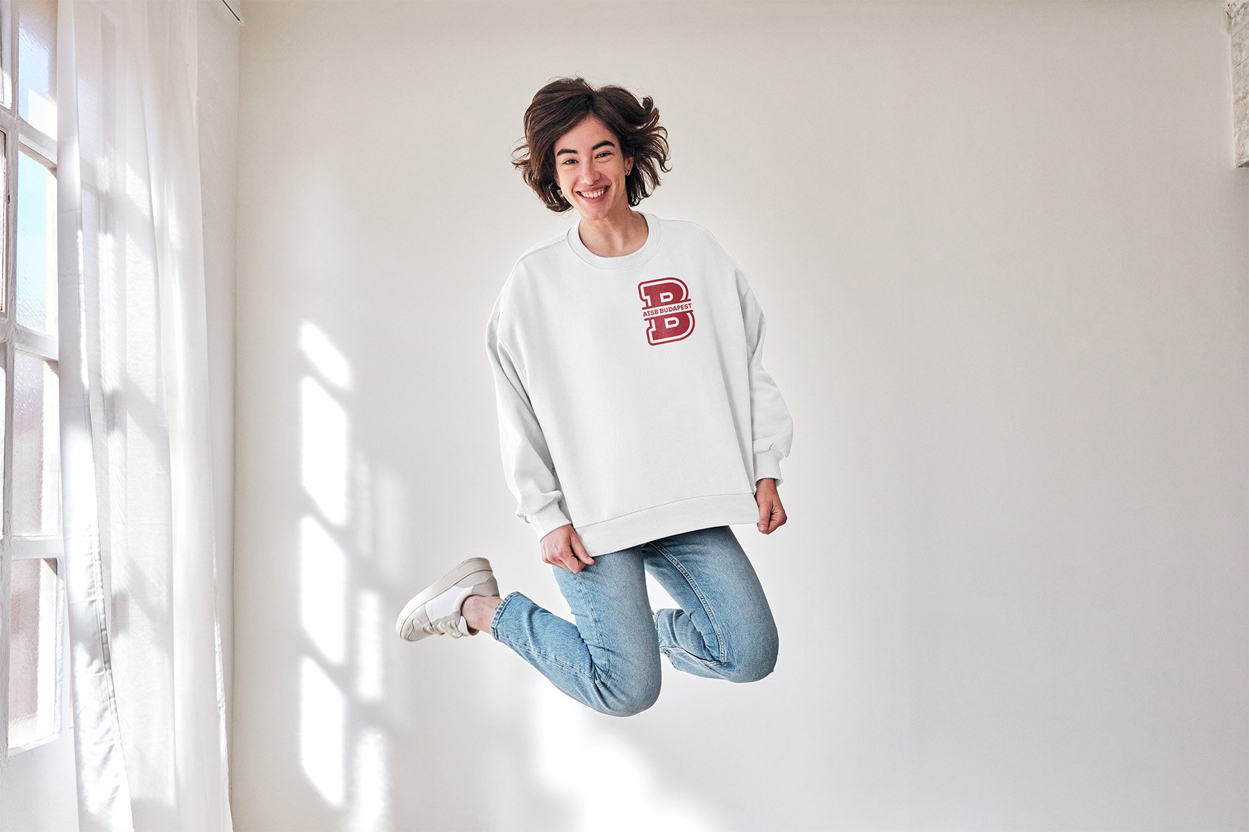 Person in white sweater with 'B' logo jumping indoors
