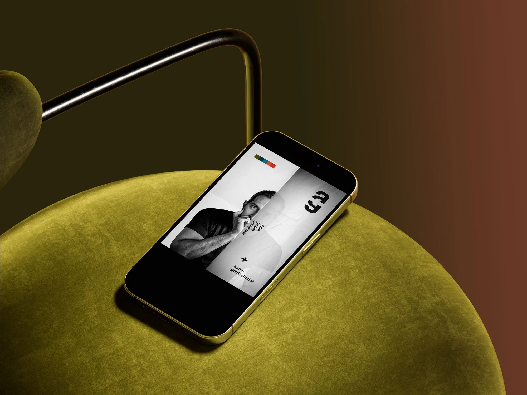 Smartphone with a black and white photo of a man on its screen, lying on a yellow velvet cushion.