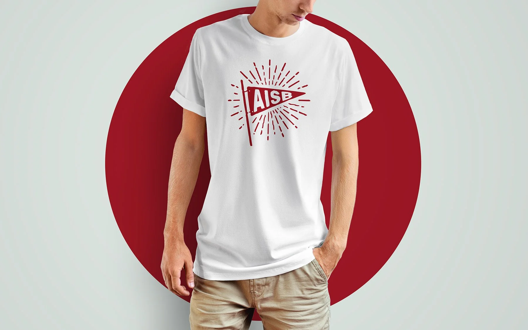 Man wearing a white T-shirt with a red AISB flag graphic in front of a red circle background.