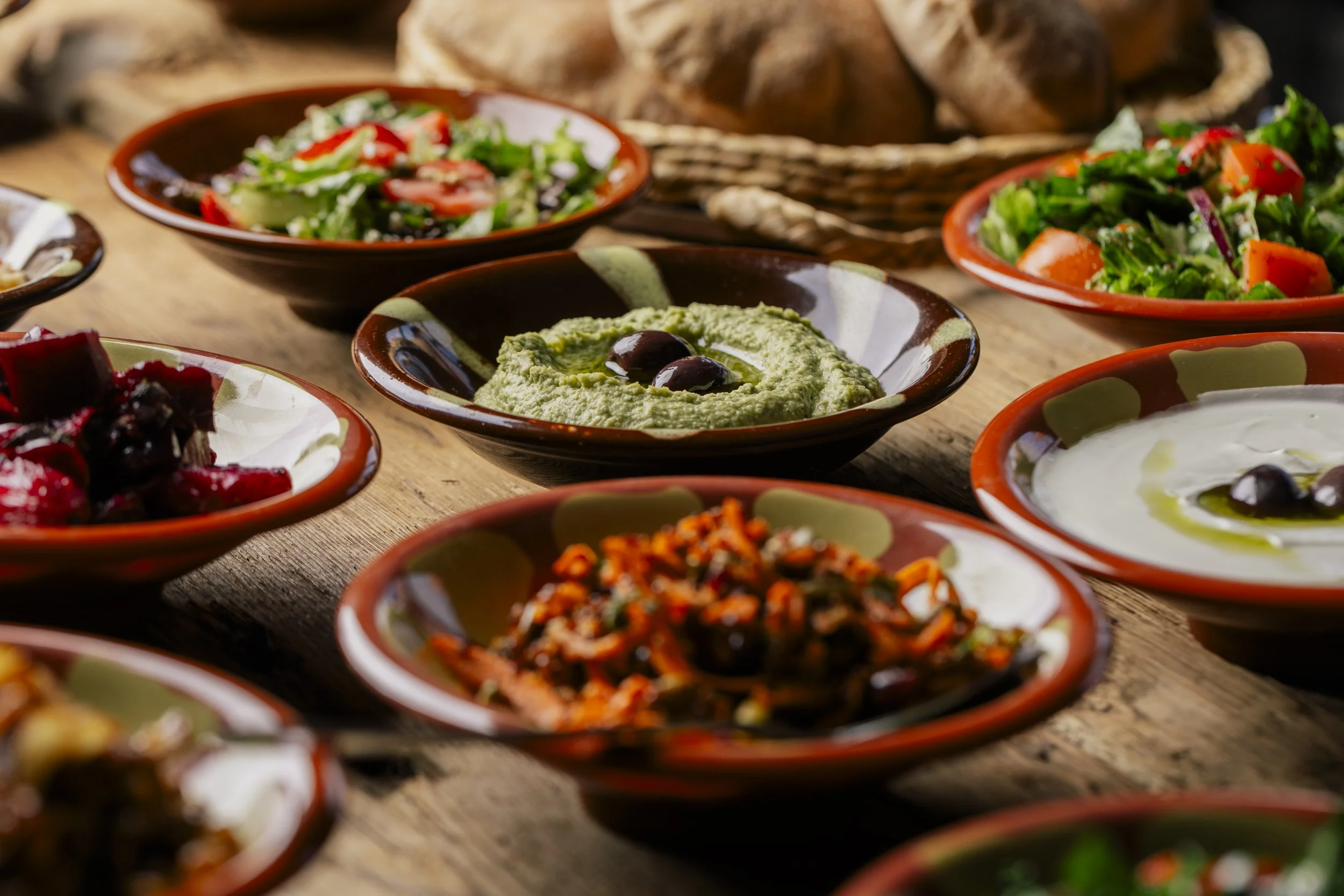 A photograph of handmade dishes, each filled with deliciously colorful dishes from Neomonde Mediterranean.
