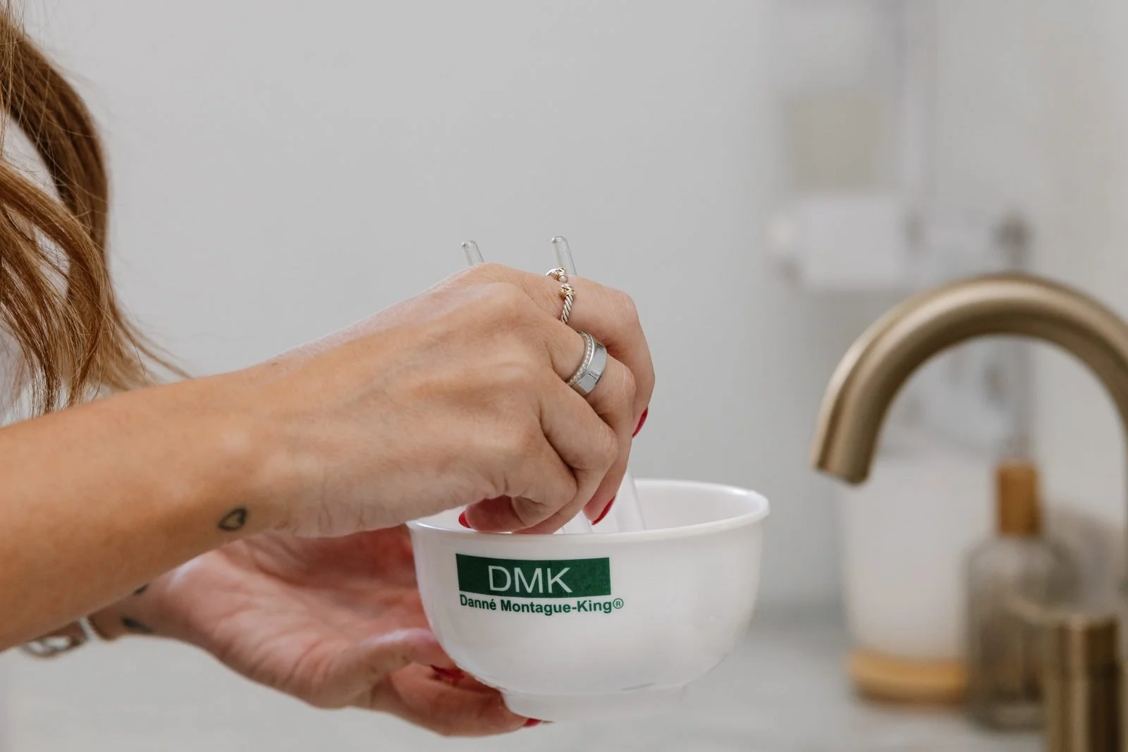 Esthetician mixing a treatment in a DMK bowl at the treatment room sink at THE SKIN FIX