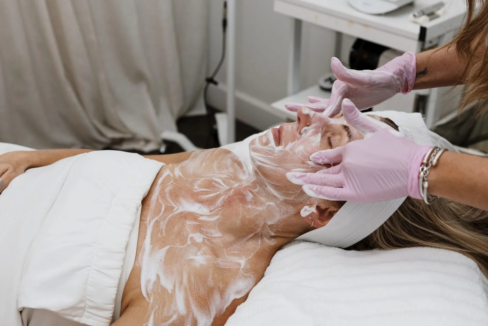 Esthetician cleansing a client's face and neck before a treatment at THE SKIN FIX