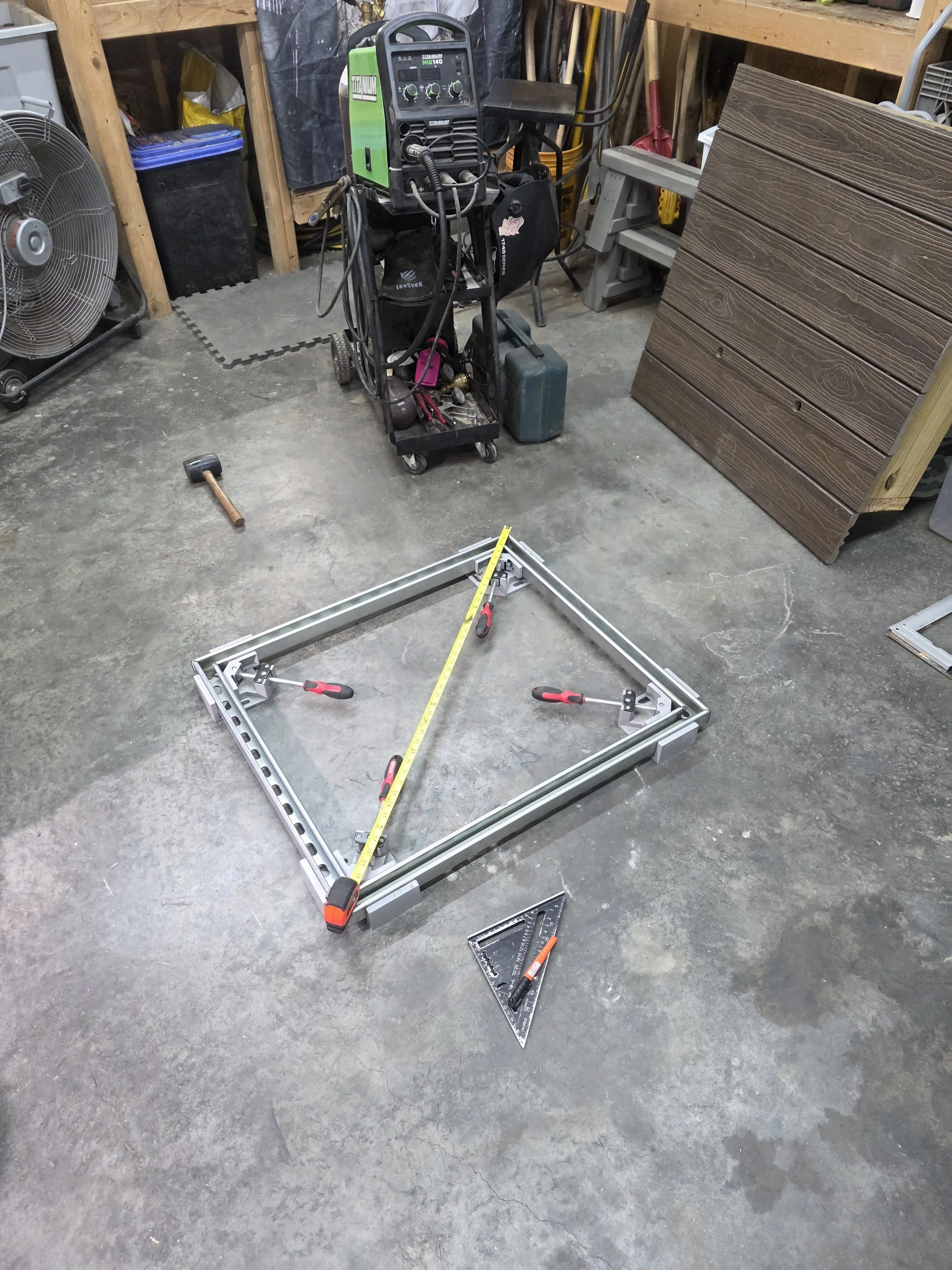 Steel pole welded to a flat metal base plate with triangular gussets at the bottom of the pole for added support, on a workshop floor.