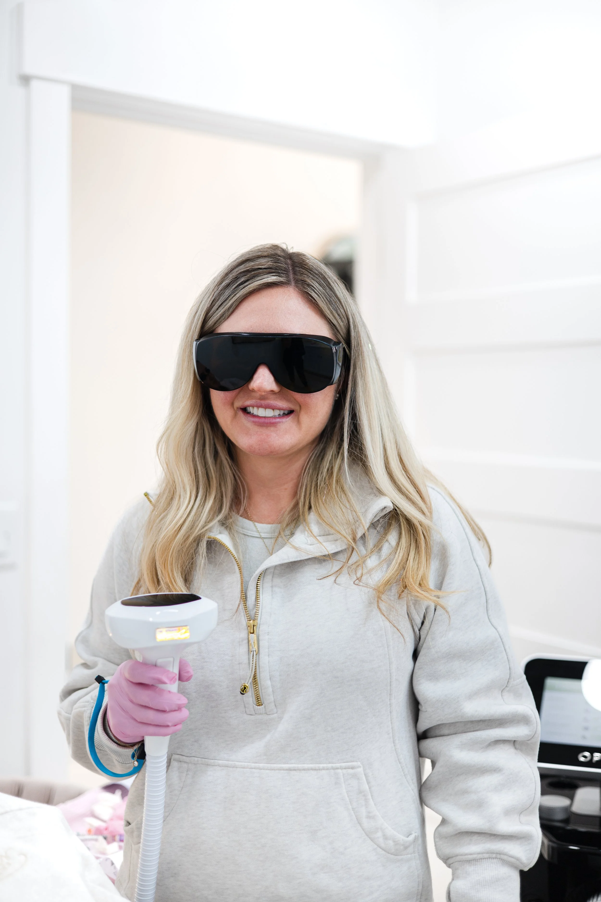 Nurse Practitioner Laura Bodine holding na IPL laser with dark protective glasses on