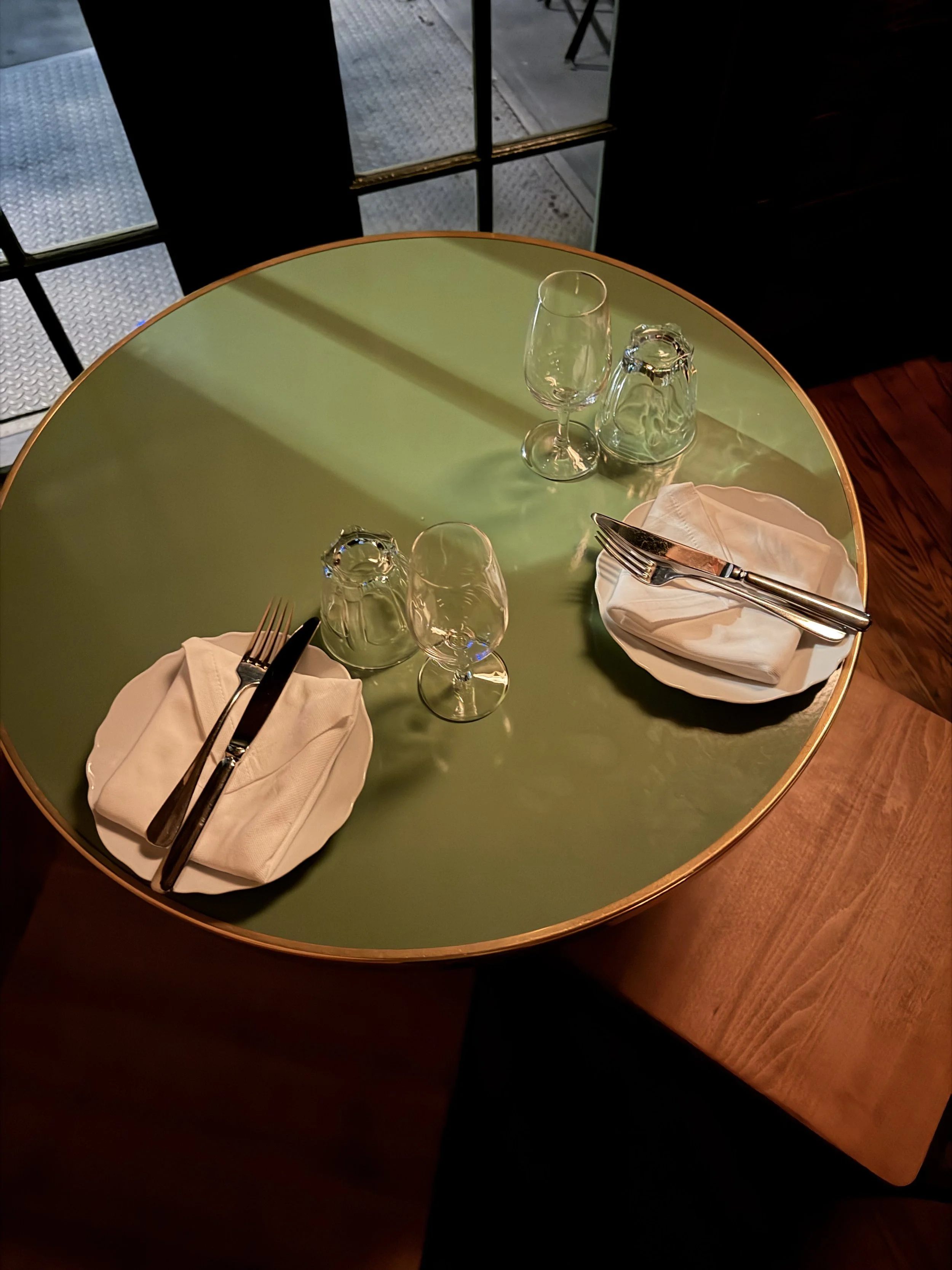 A round green table set for dinner.