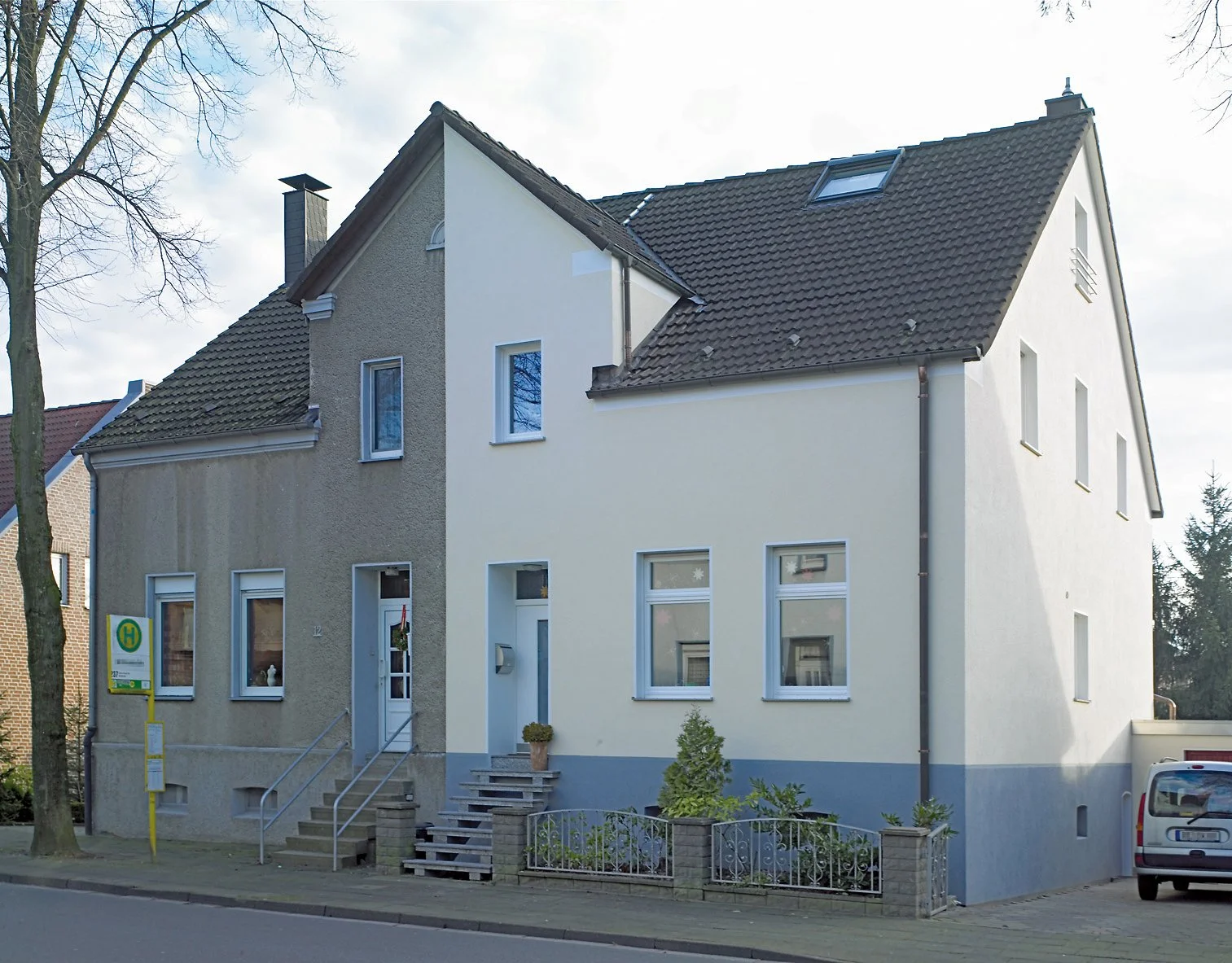 Mehrfamilienhaus mit einer sauberen, gedämmten Fassade auf der linken Seite und einer ungedämmten schmutzigen Fassade auf der rechten Seite.