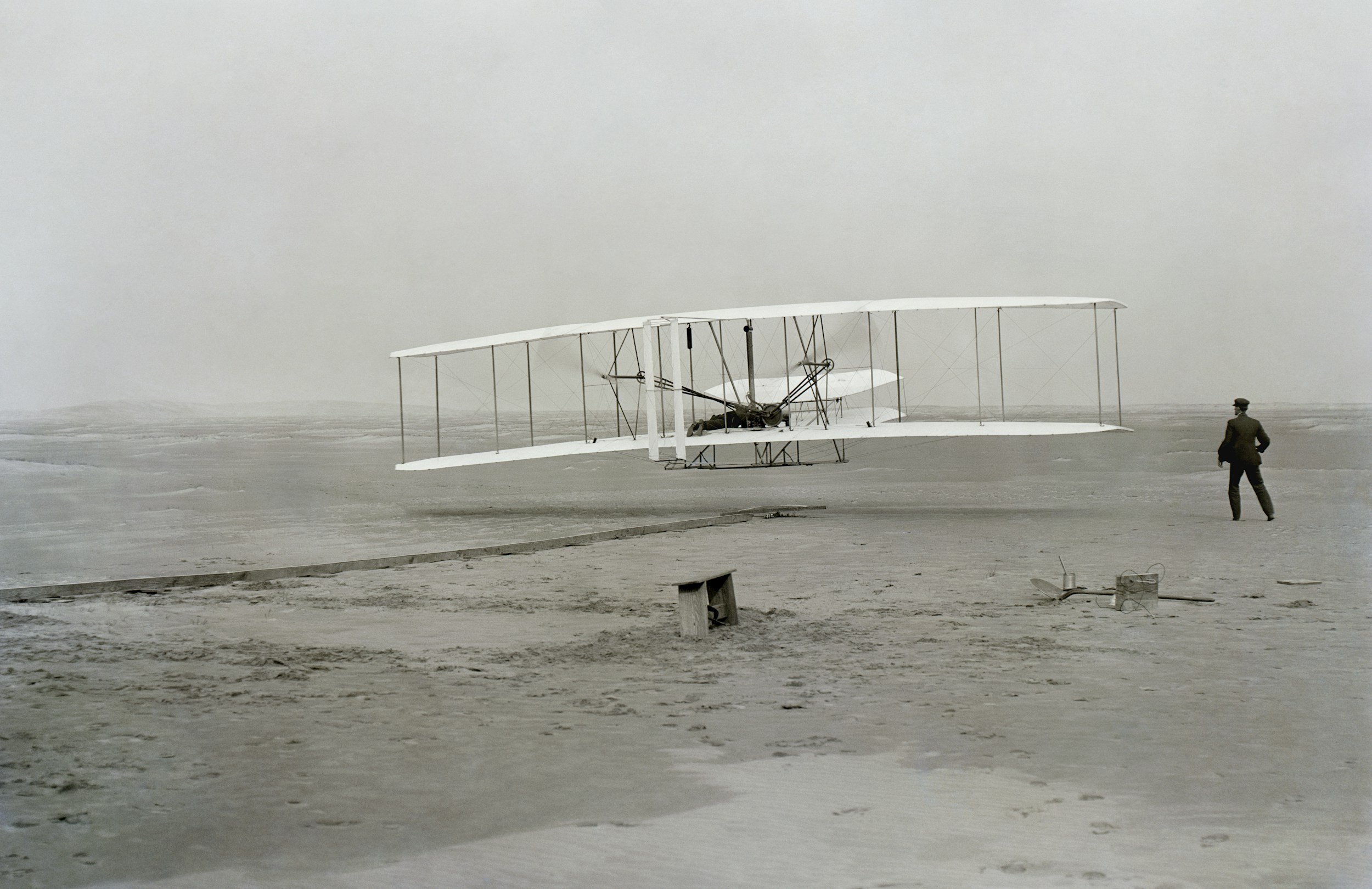 A vintage aircraft on a deserted airfield with a person standing nearby.