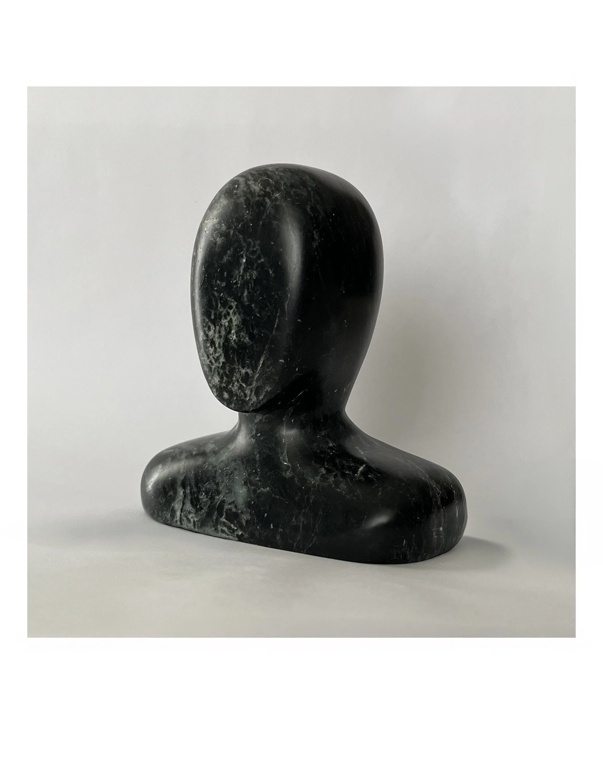 Marble sculpture of a stylized human bust on a plain background.