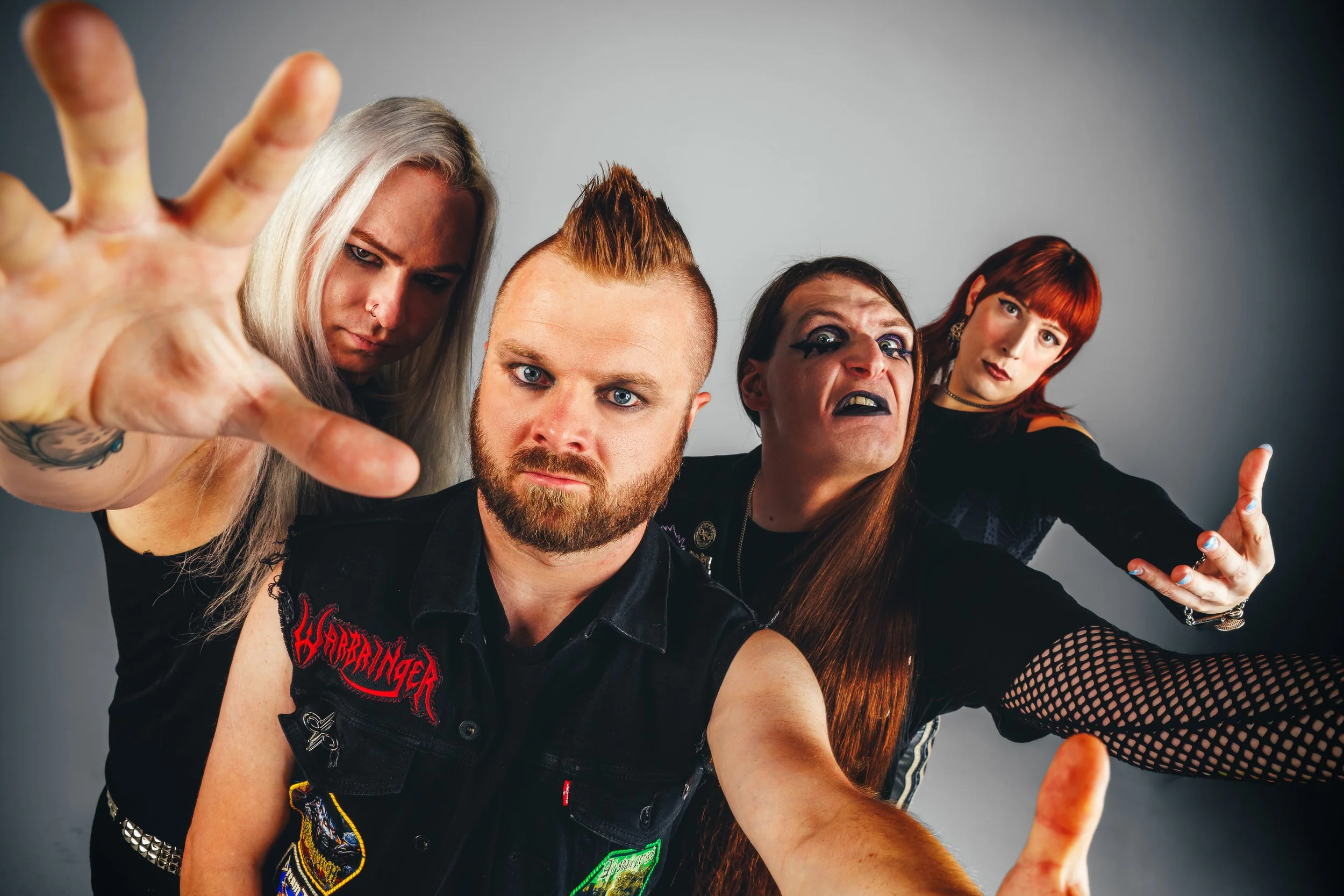 Dynamic Celestial Wizard promo photo with band members reaching toward the camera in a white cyc studio.