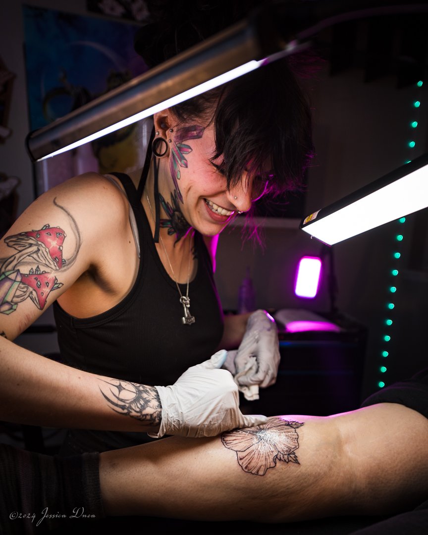 Tattoo artist smiling while cleaning a client’s new tattoo, showing the personality behind the business, by Denver photographer Jessica Dnea Imagery.