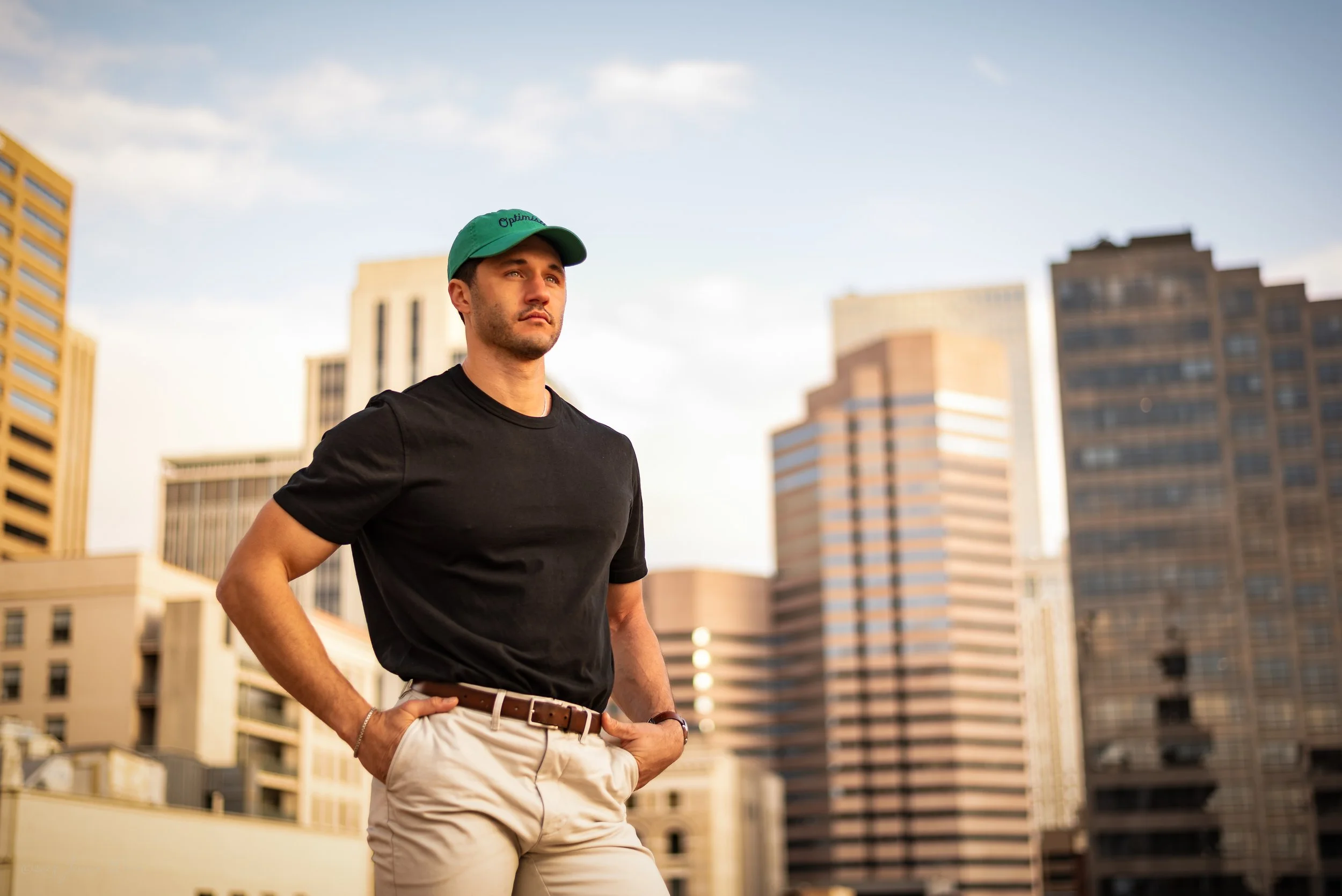 Downtown Denver personal branding portrait with city skyline views, natural light, confident posing, and a clean lifestyle look for websites, profiles, and professional marketing.