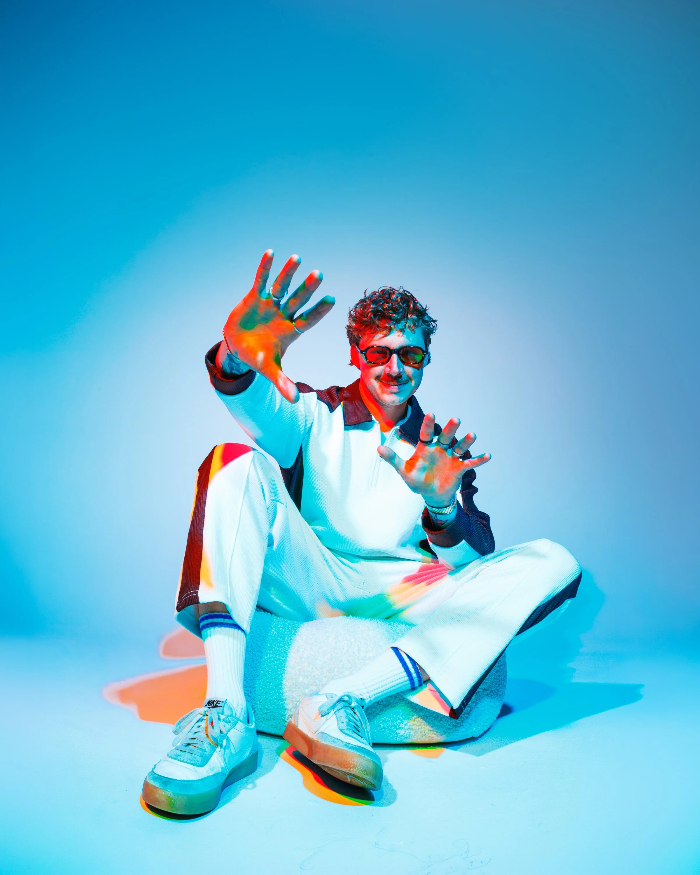 Colorful Denver musician press portrait with blue, red, and orange studio lighting, playful posing, and bold creative direction for artist branding and promotional use.