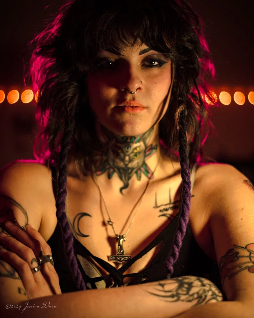 Dramatic creative branding portrait of a tattoo artist with pink rim lighting and warm background lights by Jessica Dnea Imagery.