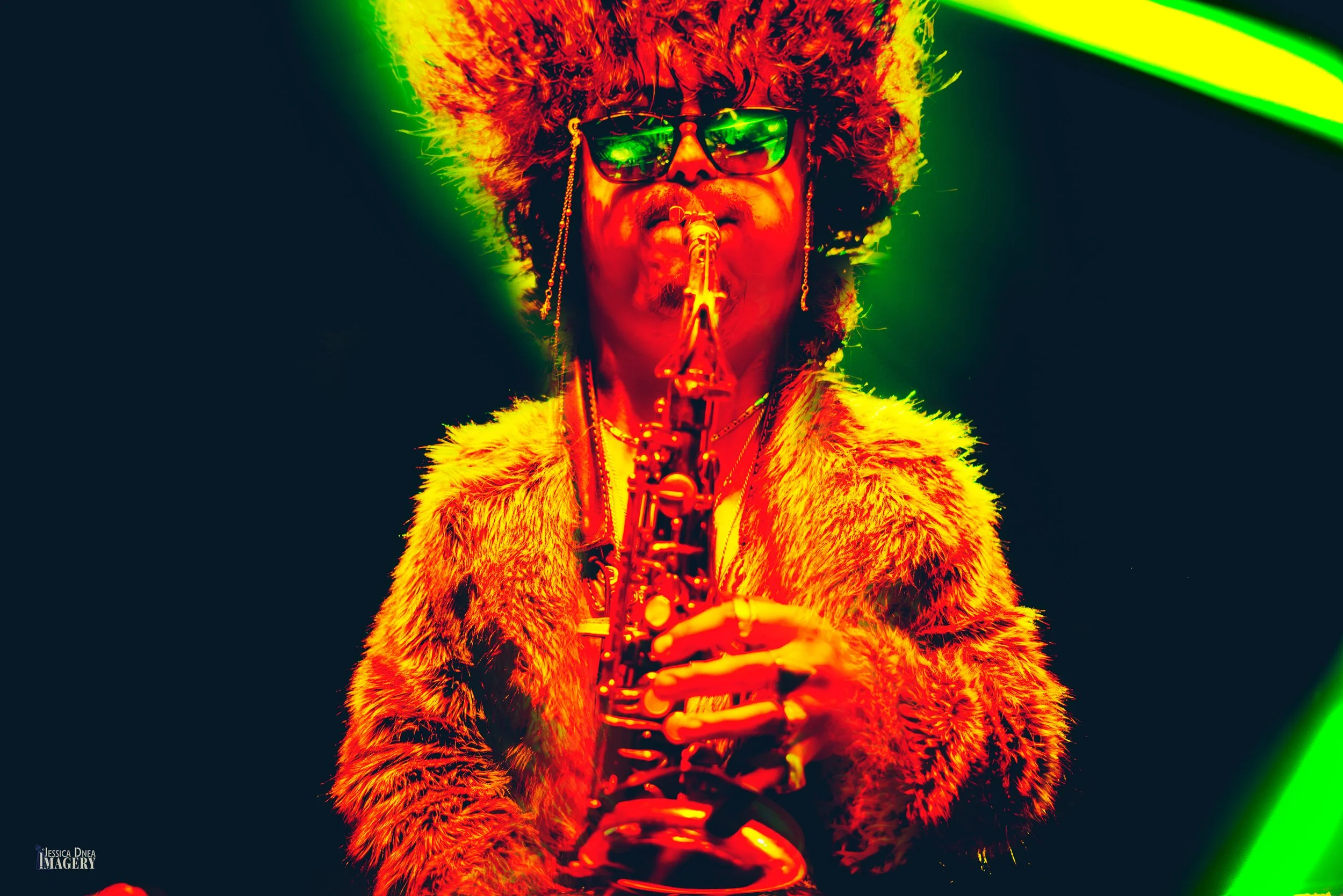 A Boogie Lights saxophonist performs in a fur hat and sunglasses beneath saturated red and green lighting at Globe Hall in Denver.