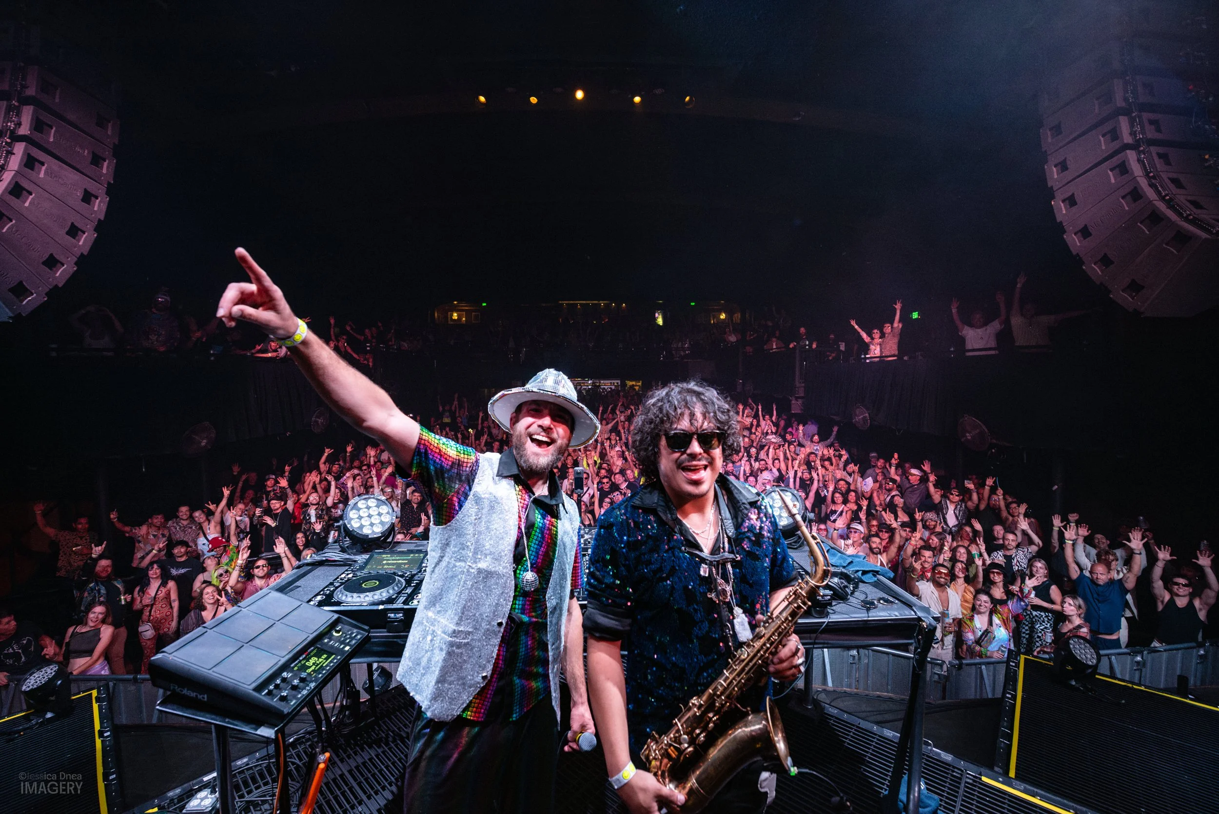 Boogie Lights performers pose onstage before a packed Ogden Theatre audience in a wide Denver concert and crowd photograph.