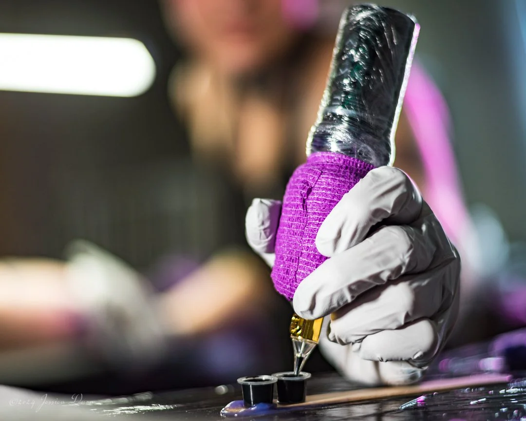 Detail photograph of a tattoo artist holding a tattoo machine during a client session, created for Denver personal branding, business storytelling, websites, and promotional content.