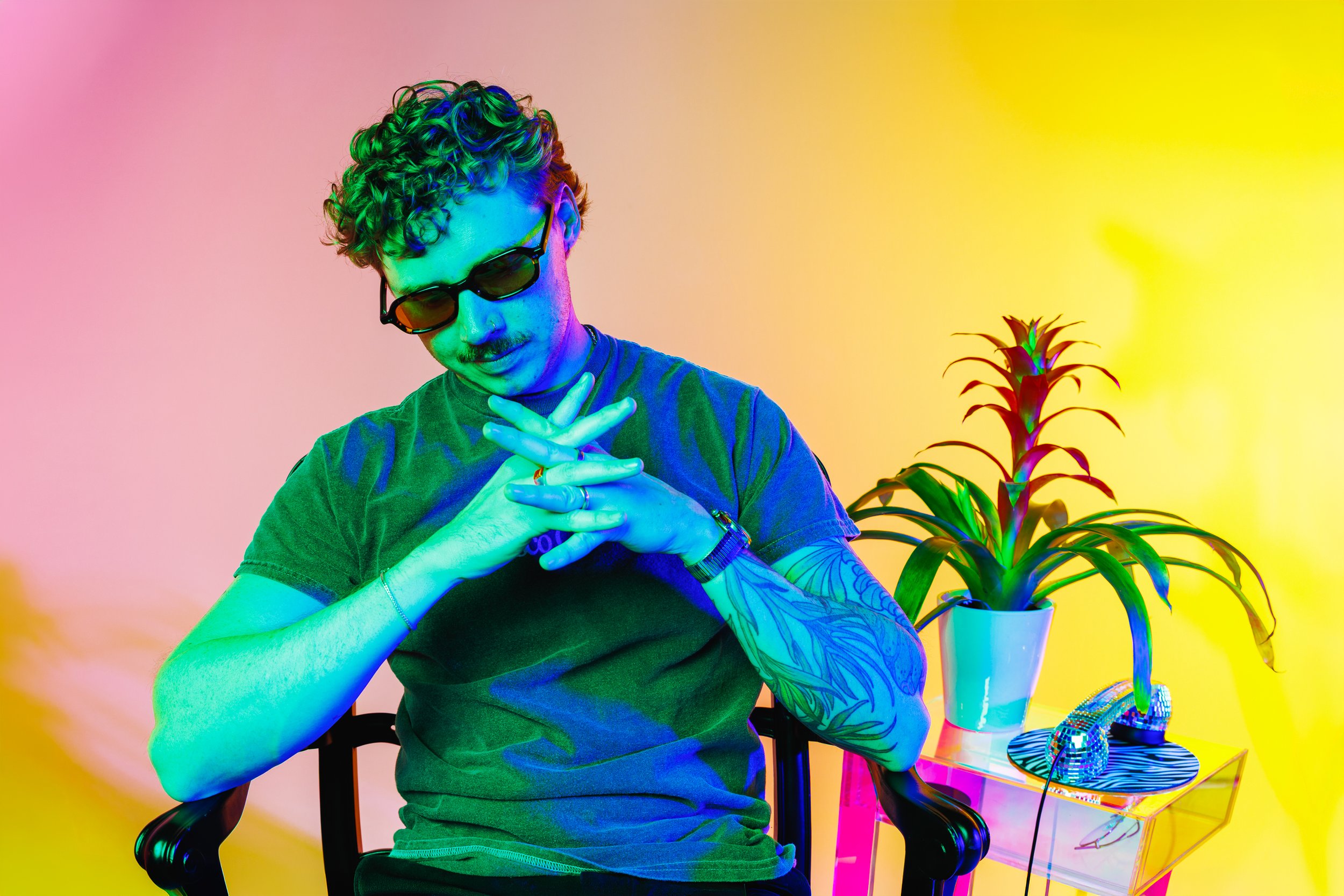 Colorful Denver artist branding portrait with saturated green, blue, pink, and yellow lighting, retro styling, and a creative studio environment for press and promotional campaigns.