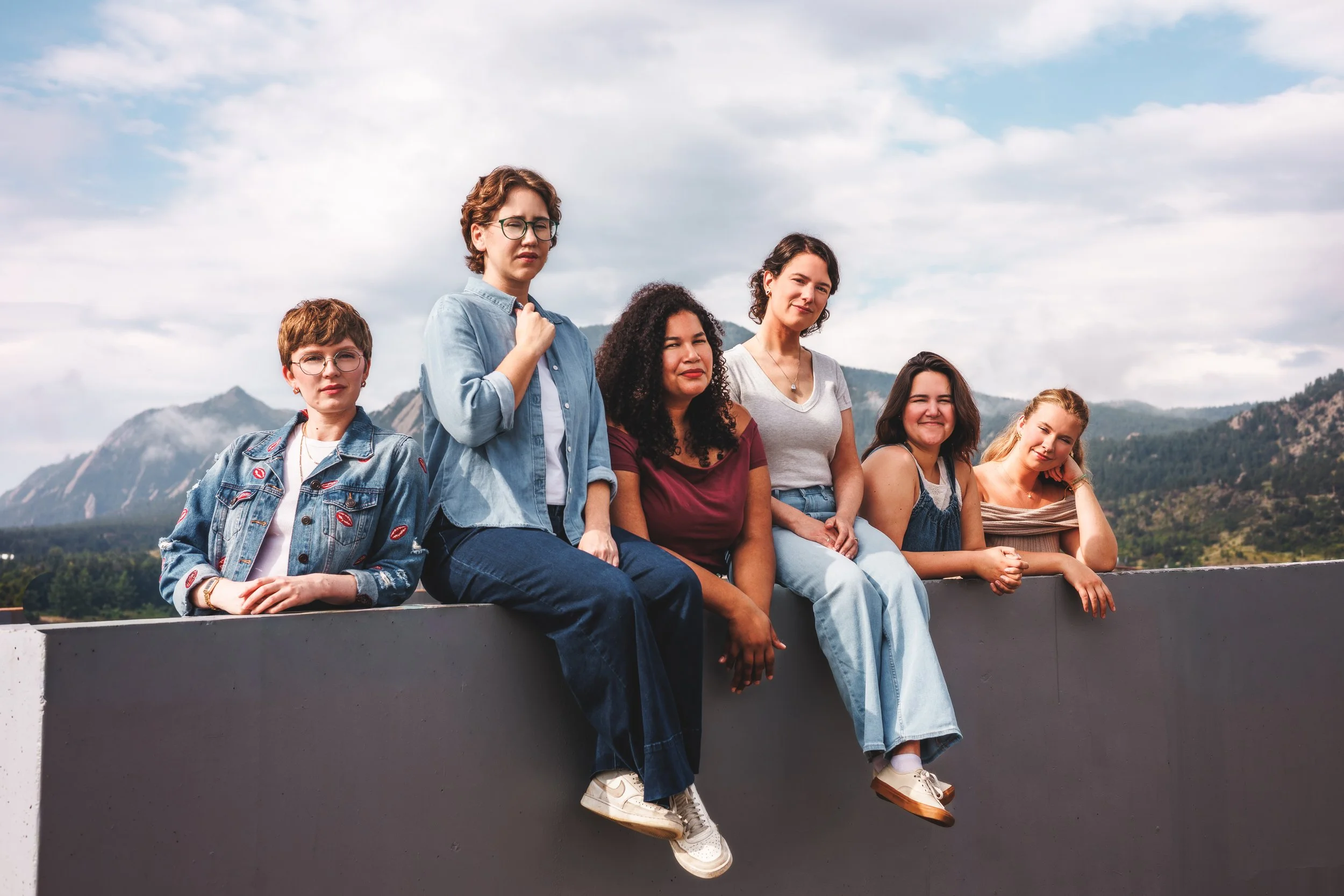 Six-member creative team seated together against a rooftop wall during a full branding session by Denver photographer Jessica Dnea Imagery.